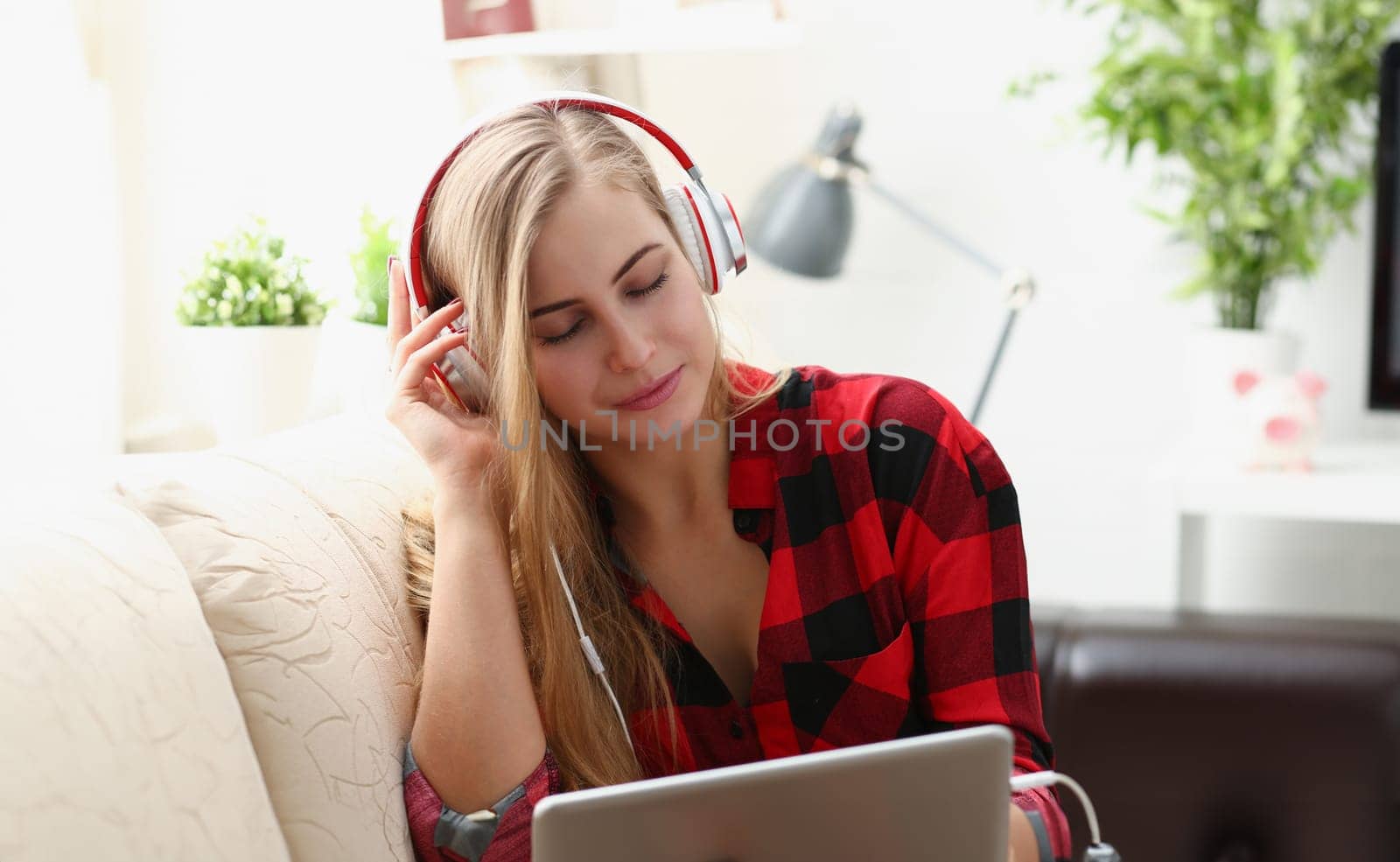 blond young pretty woman work on laptop listen music headphones