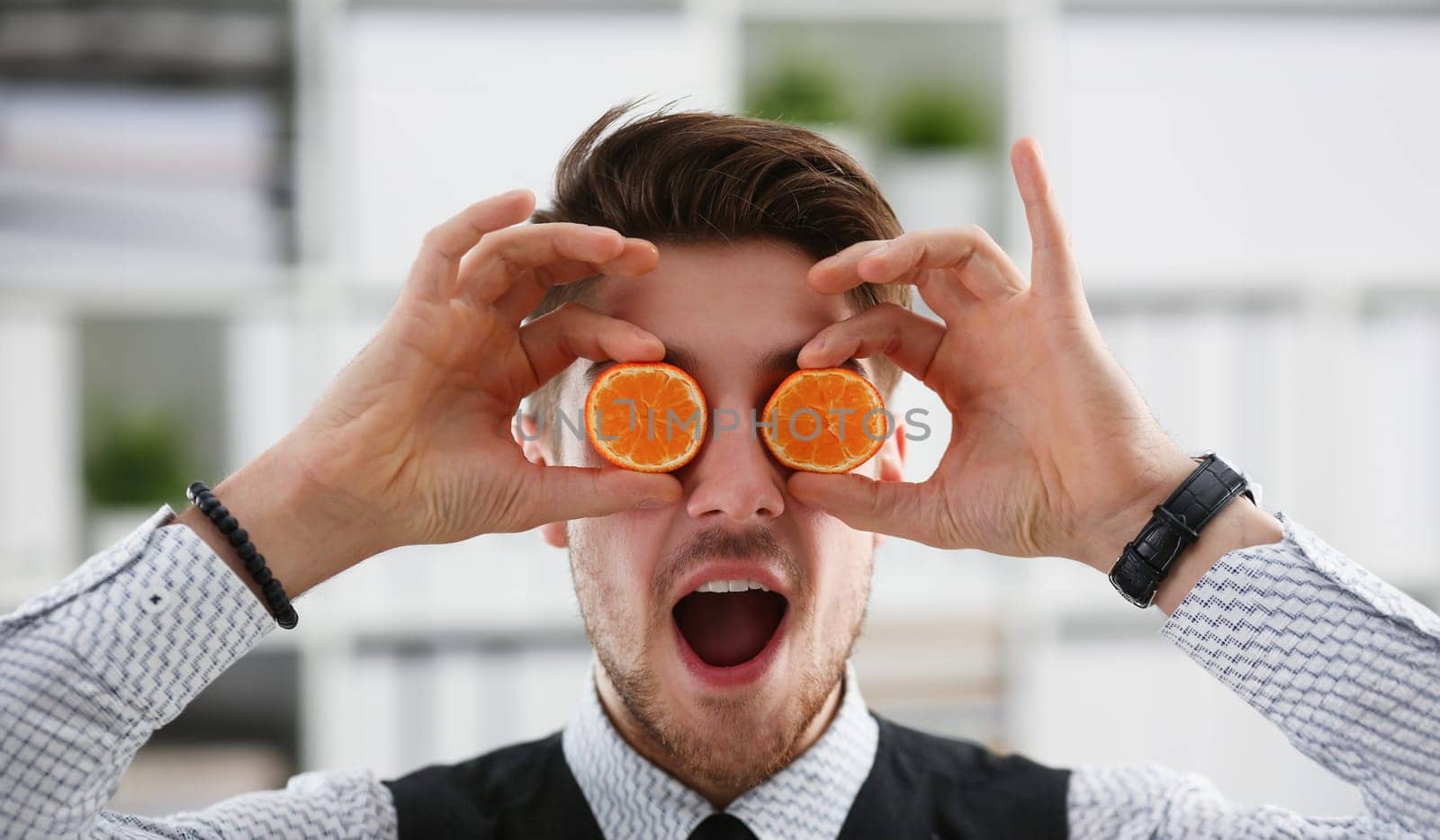 Male hands hold a cut fruit at eye level instead of glasses. The theme of a healthy diet for withdrawal activities and belief in diet achievements in business and education.