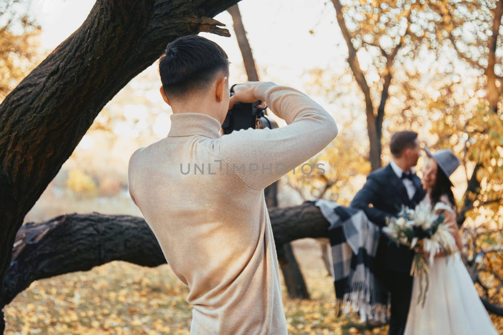 Professional wedding photographer taking pictures of the bride and groom on the wedding day. in autumn