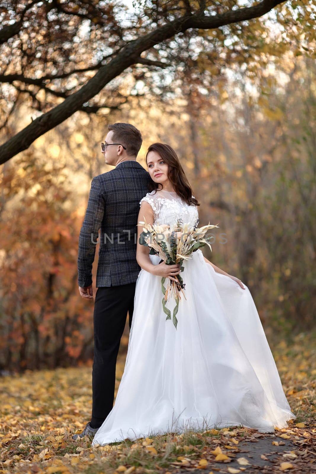 beautiful sensual bride in white wedding dress and groom standing outdoor on natural background