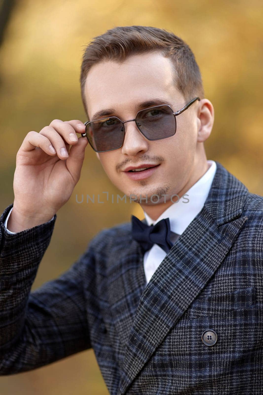 Handsome young man in classic checked suit and sunglasses outdoor
