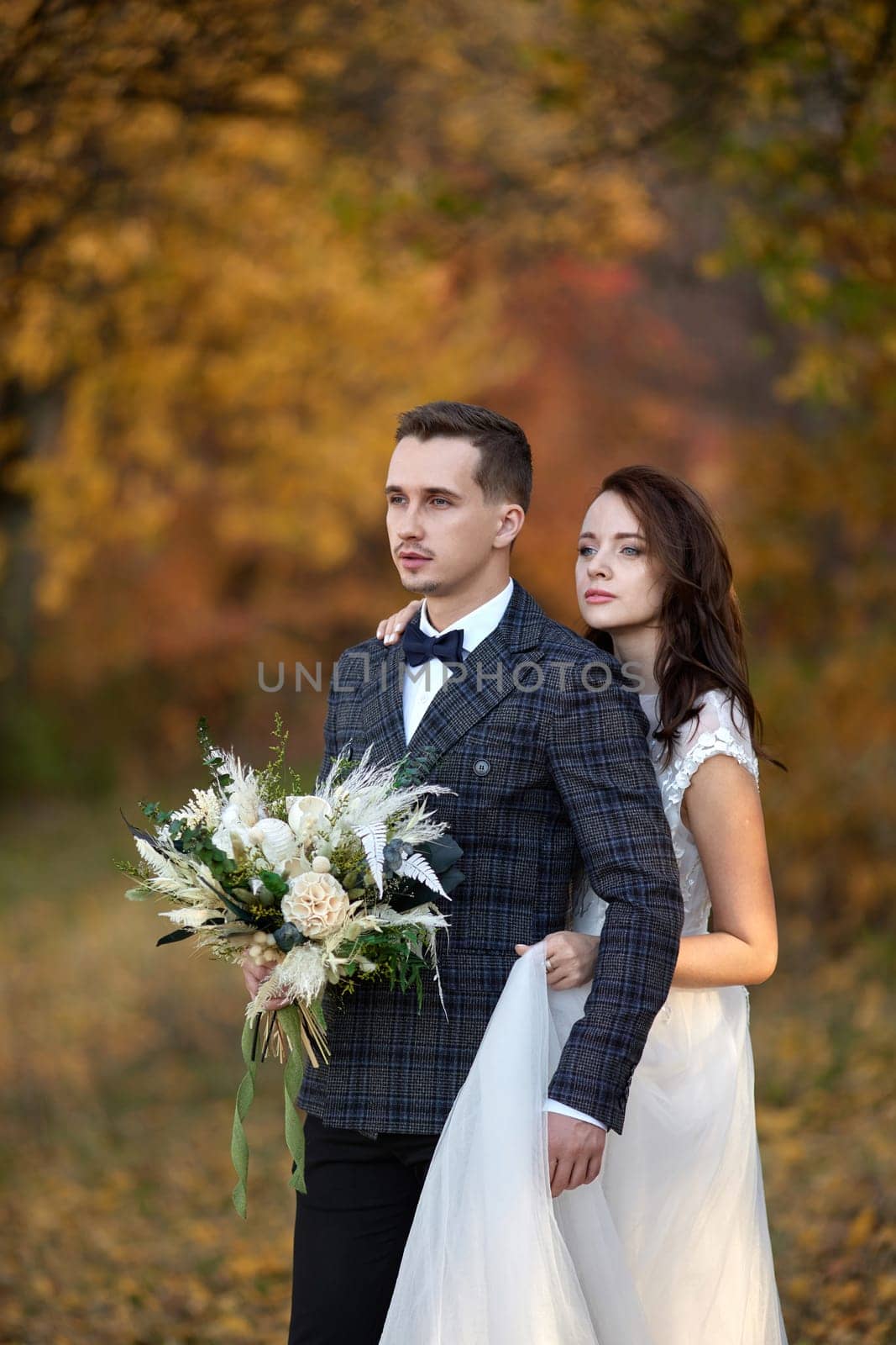 beautiful sensual bride in white wedding dress and groom standing outdoor on natural background