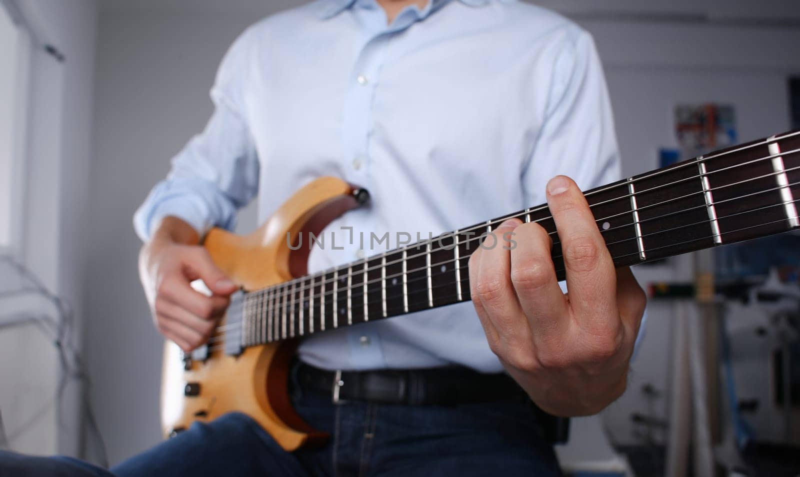 Male arms holding and playing classic shape wooden electric guitar closeup. Six stringed learning musical school education art leisure electrical vintage stage shop having fun enjoying hobby concept