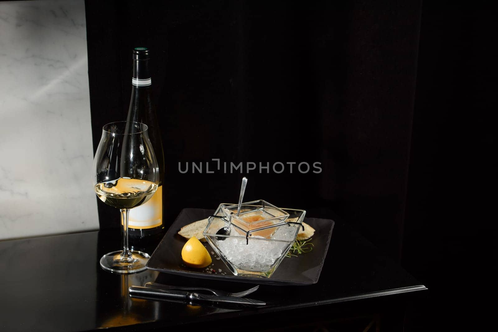 Pike fish caviar, on ice, with croutons, lemon, on a transparent dish, on a dark background by Ashtray25