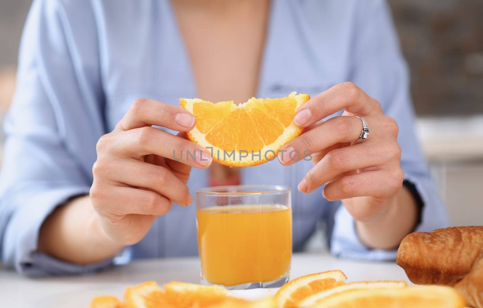 Female arms hold slides orange and glass of juice at kitchen table closeup. Weight loss beauty fit concept