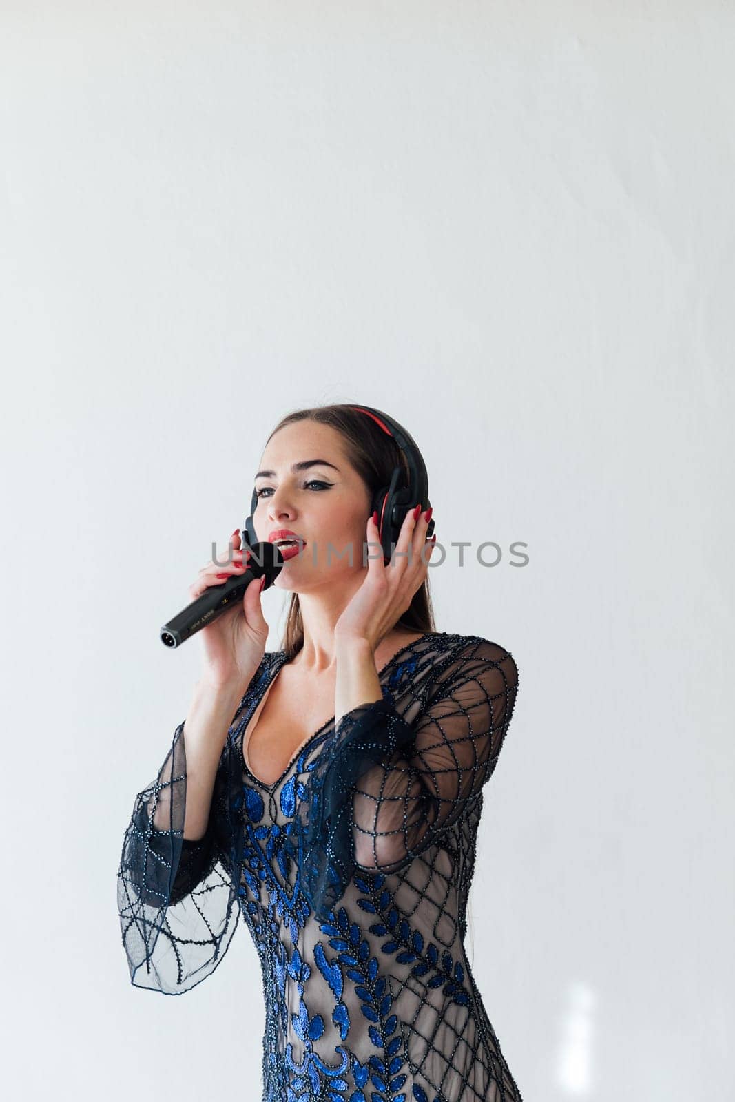 Brunette woman in beautiful festive clothes on a white background singing singer