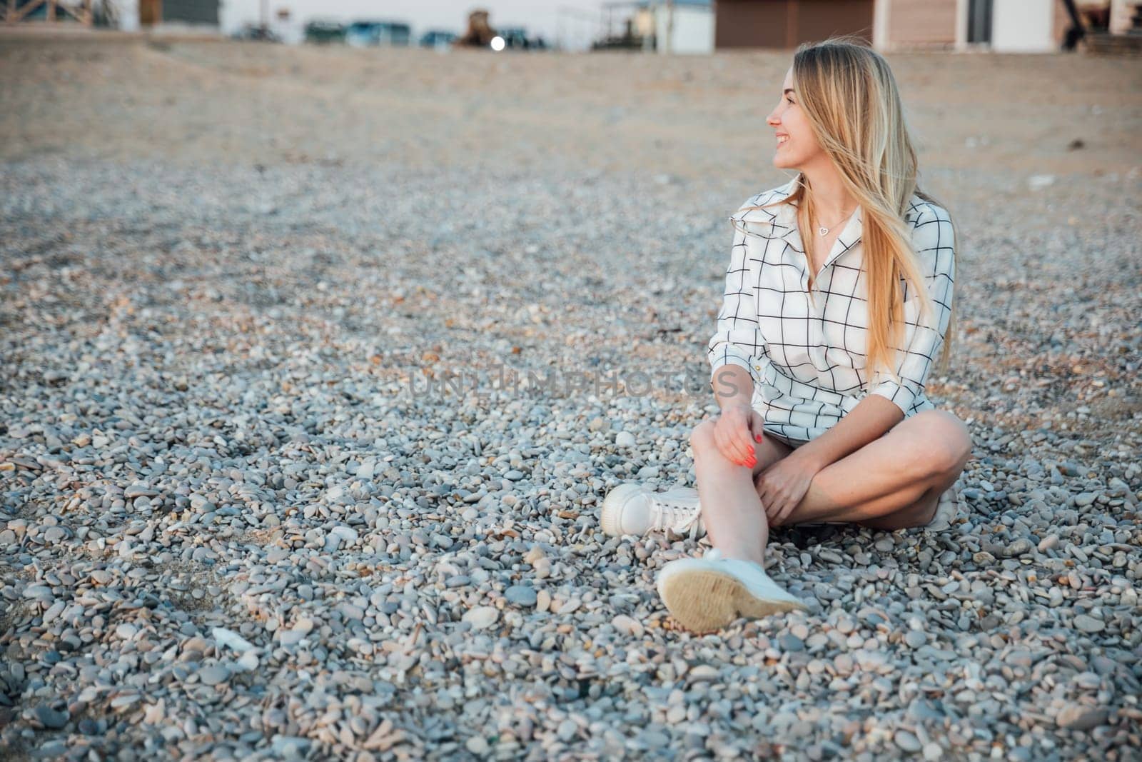 Blonde sitting on pebbles on the beach for a walk