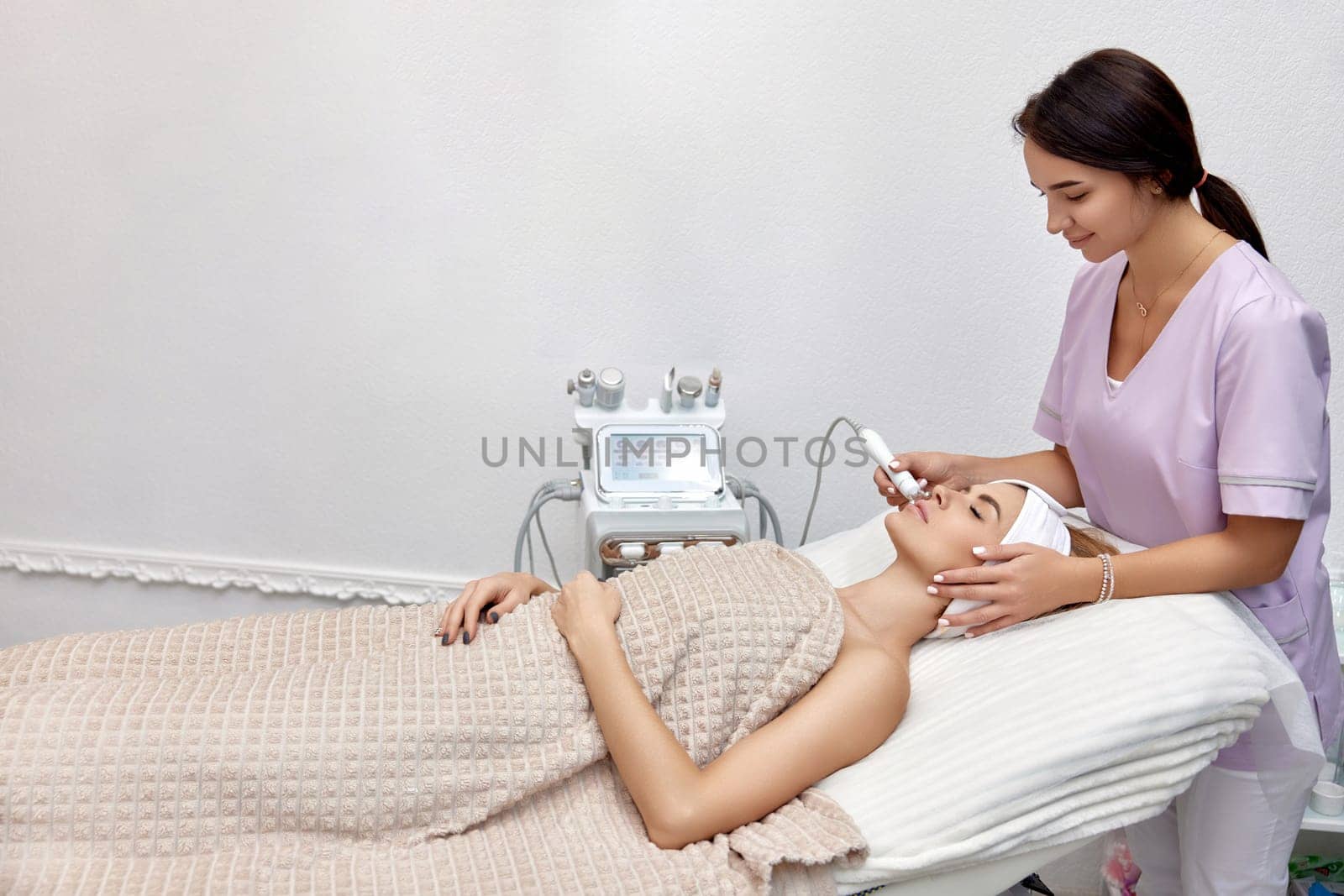 cosmetologist making procedure microdermabrasion on the face in beauty salon