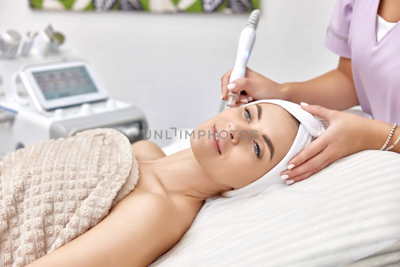 cosmetologist making procedure microdermabrasion on the face in beauty salon