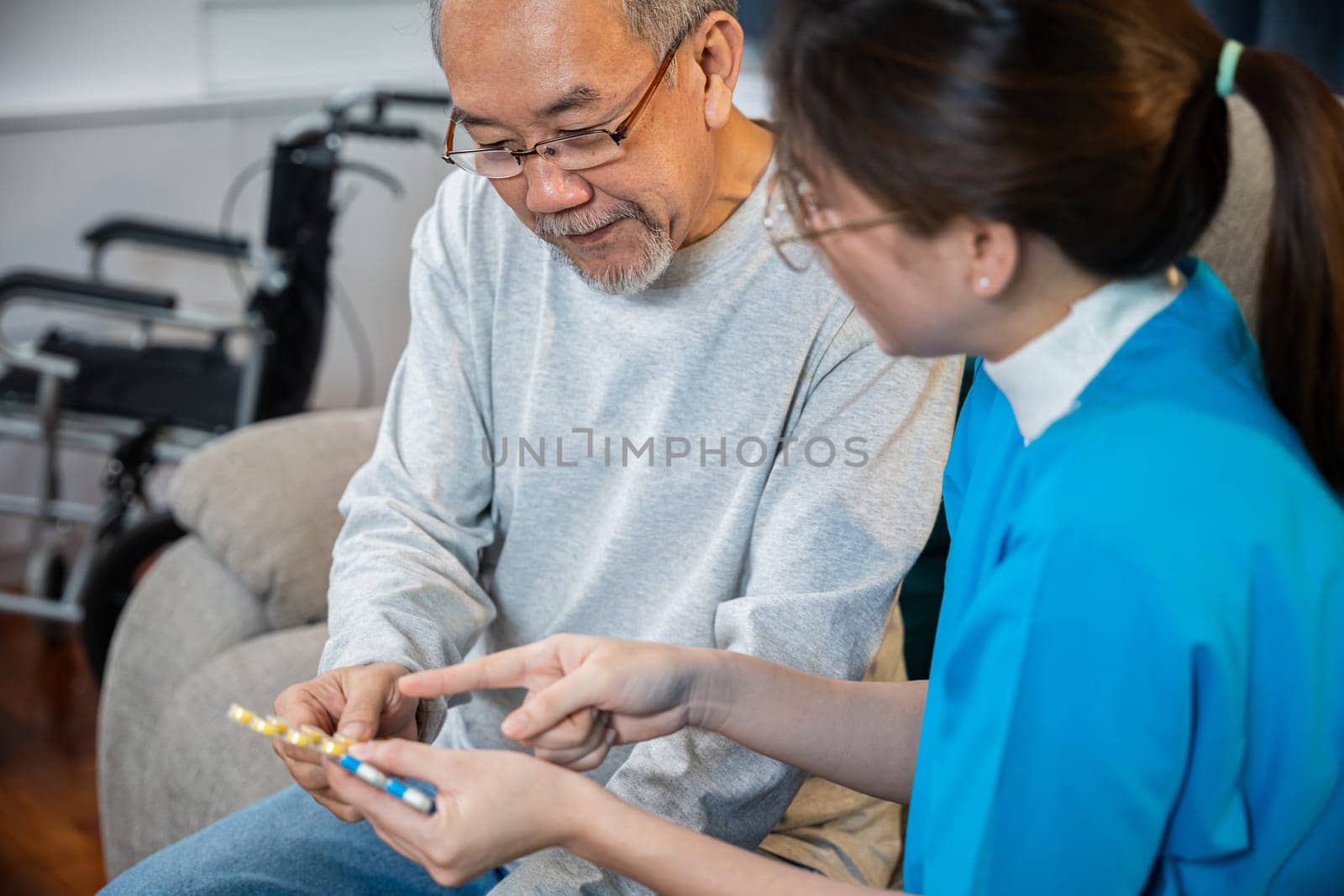 Woman nurse caregiver showing prescription drug to senior man at nursing home, healthcare support, Asian doctor with physician visit senior male patient consult medicine dosage at house in living room