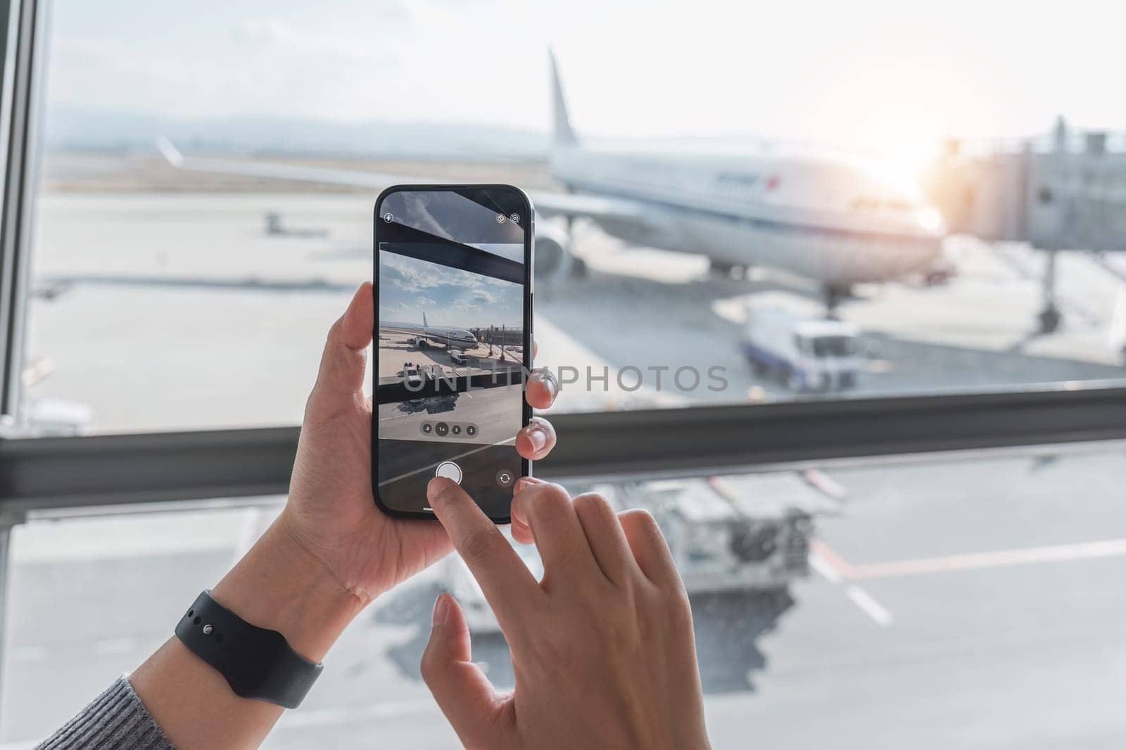 Closeup of a woman using a cell phone at the airport, taking photos or researching travel information..