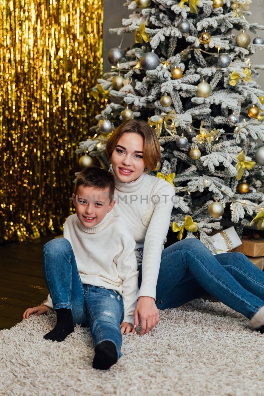 Mom with son at christmas tree with gifts new year