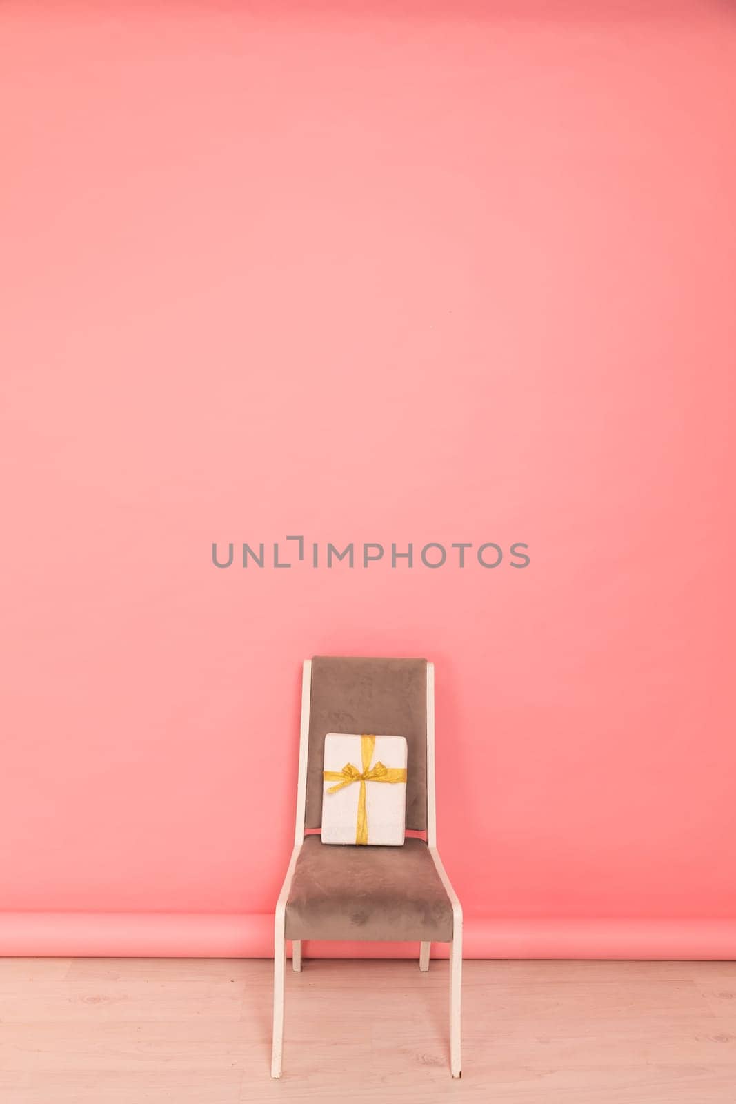 Chair With Holiday Gift Against Bright Colored Wall