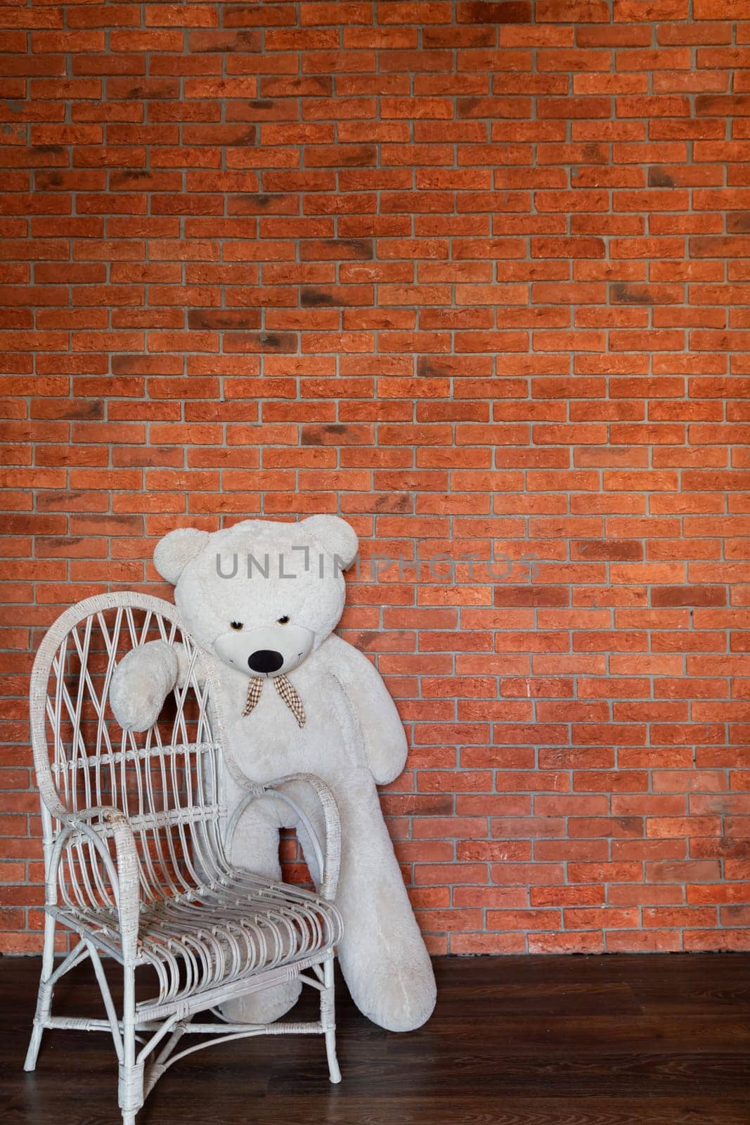 White Polar Bear Toy By Armchair In Room With Brick Wall by Simakov