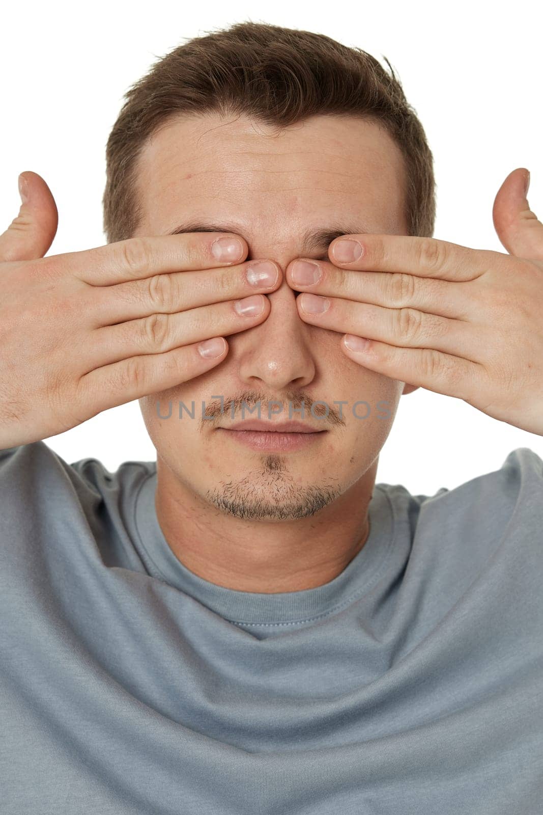 man covering eyes with hands on white background