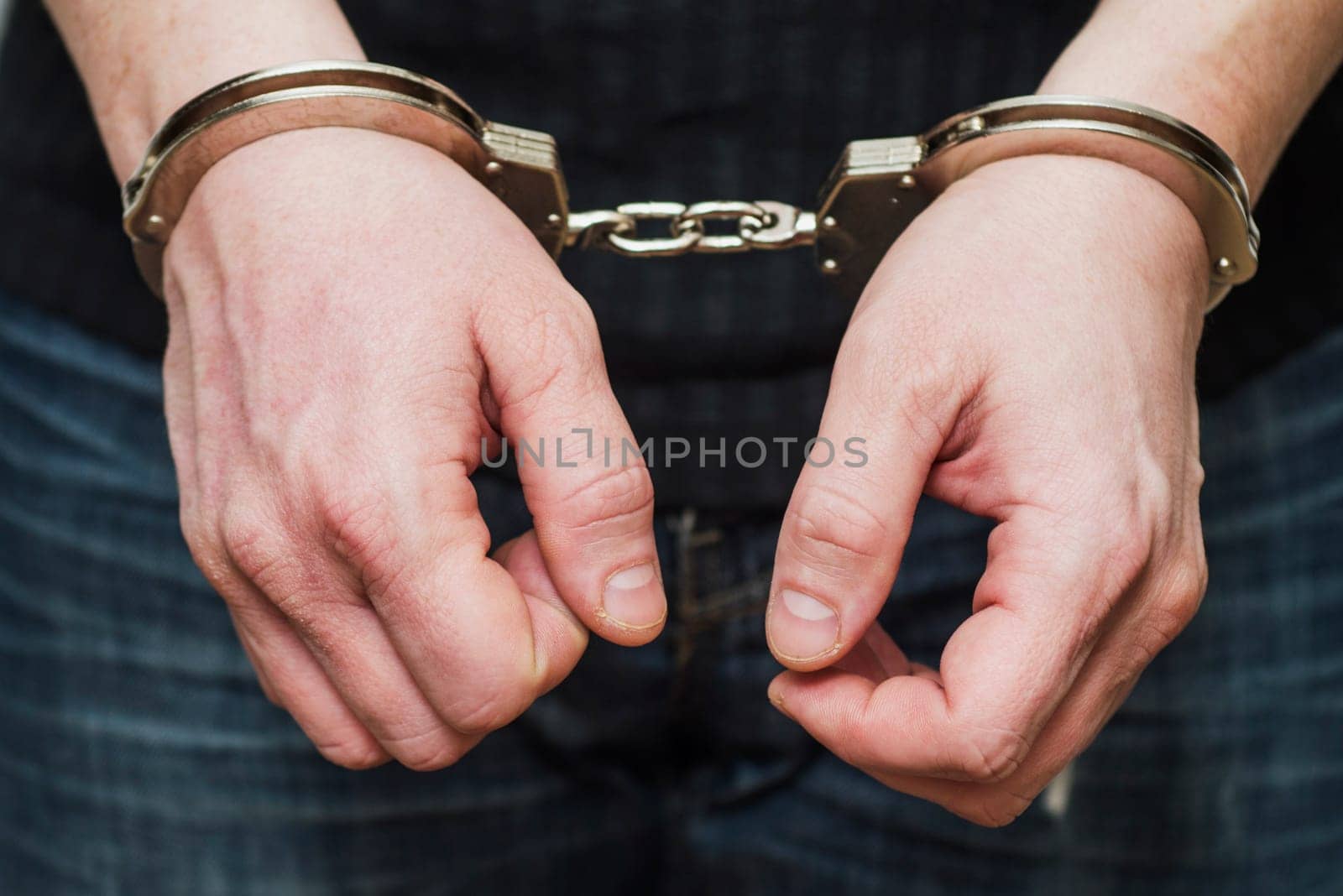 Man detained in handcuffs. Prisoner or arrested man in handcuffs. Male hands in handcuffs. Criminal law.