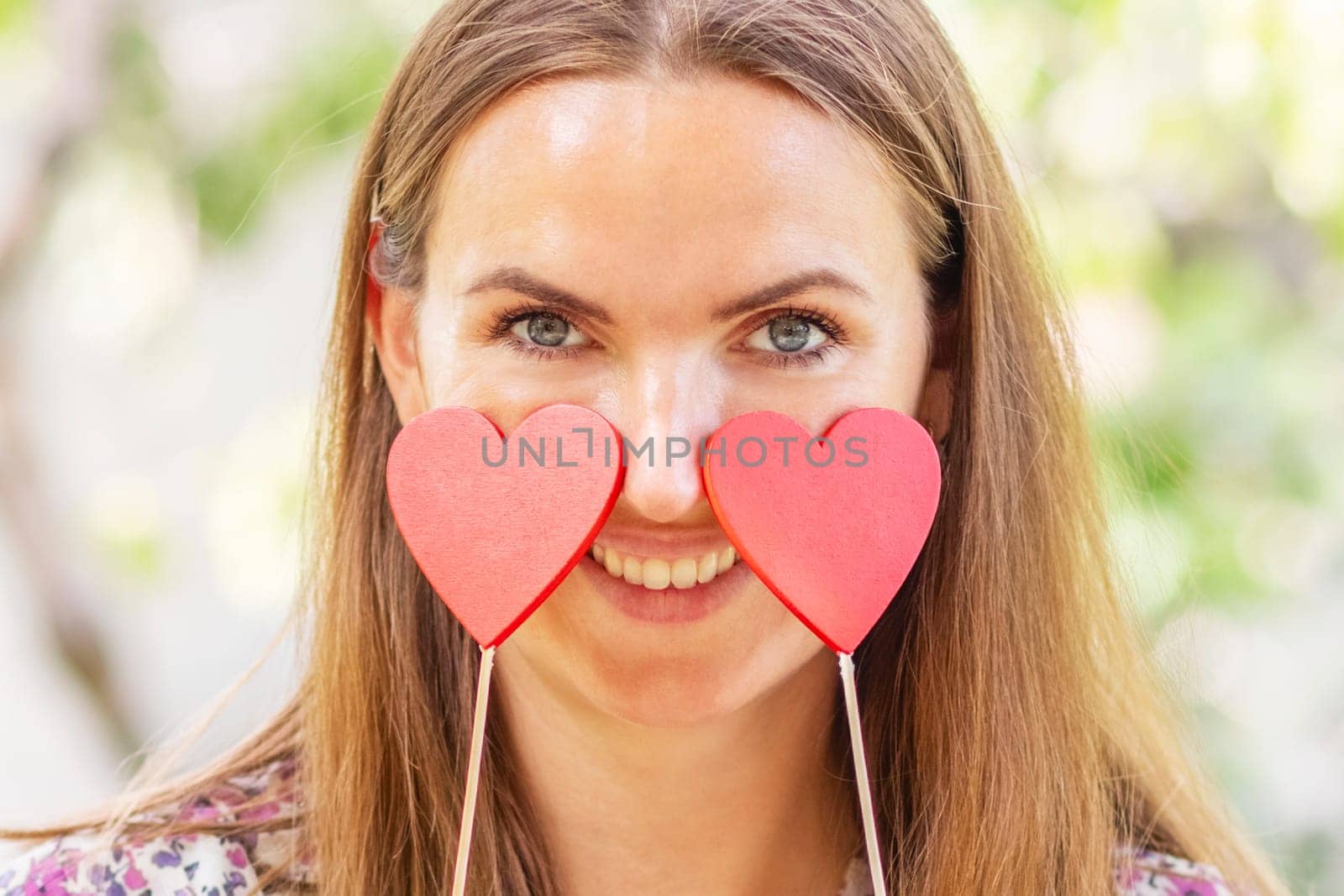 Woman with two decorative hearts in her hands smiling on natural background by andreyz