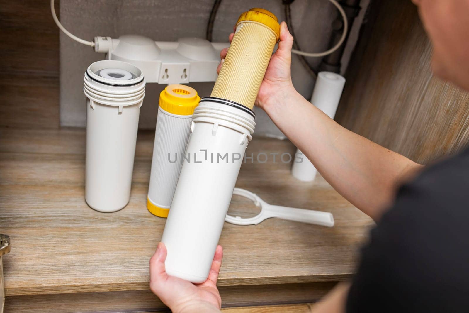 Plumber installs or change water filter. Replacement aqua filter. Repairman installing water filter cartridges in a kitchen. Clean water at home.
