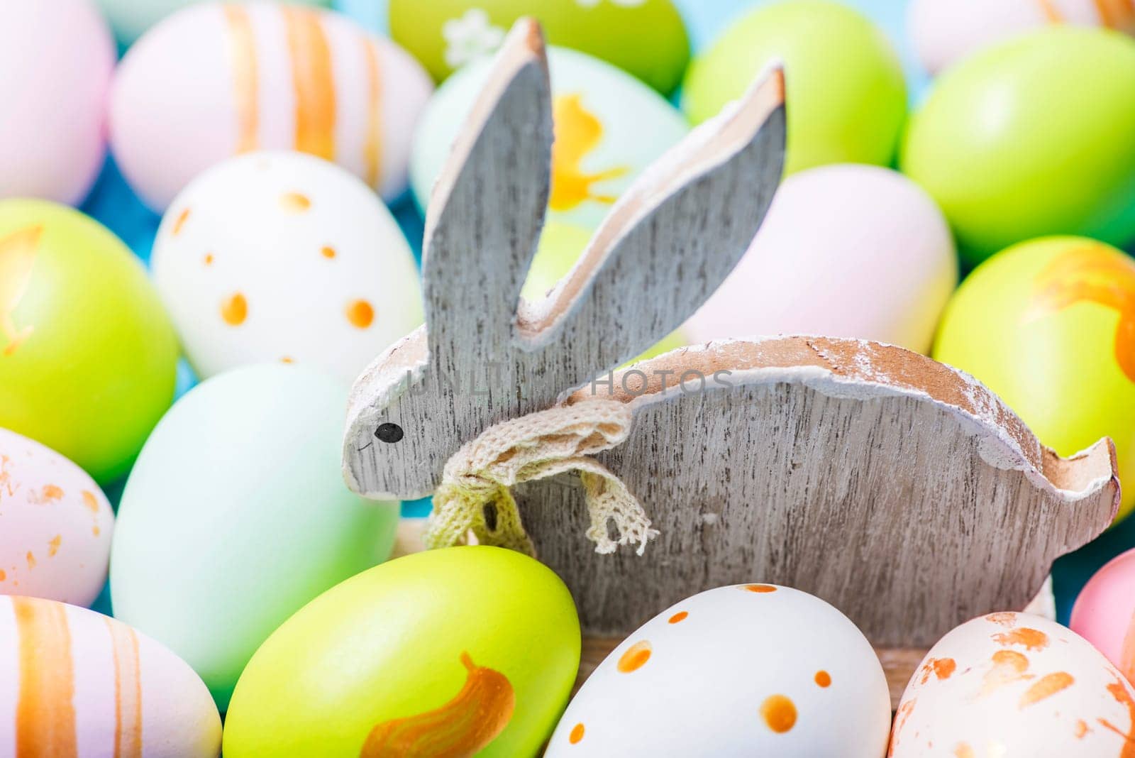 Colorful Easter eggs and wooden rabbit. Cute rabbit among Easter eggs.