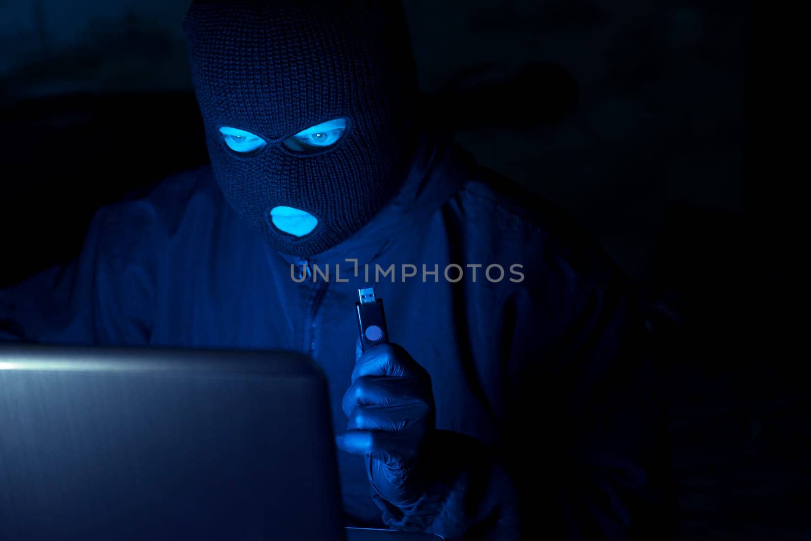 Masked hacker stealing data and personal identity information off laptop by andreyz