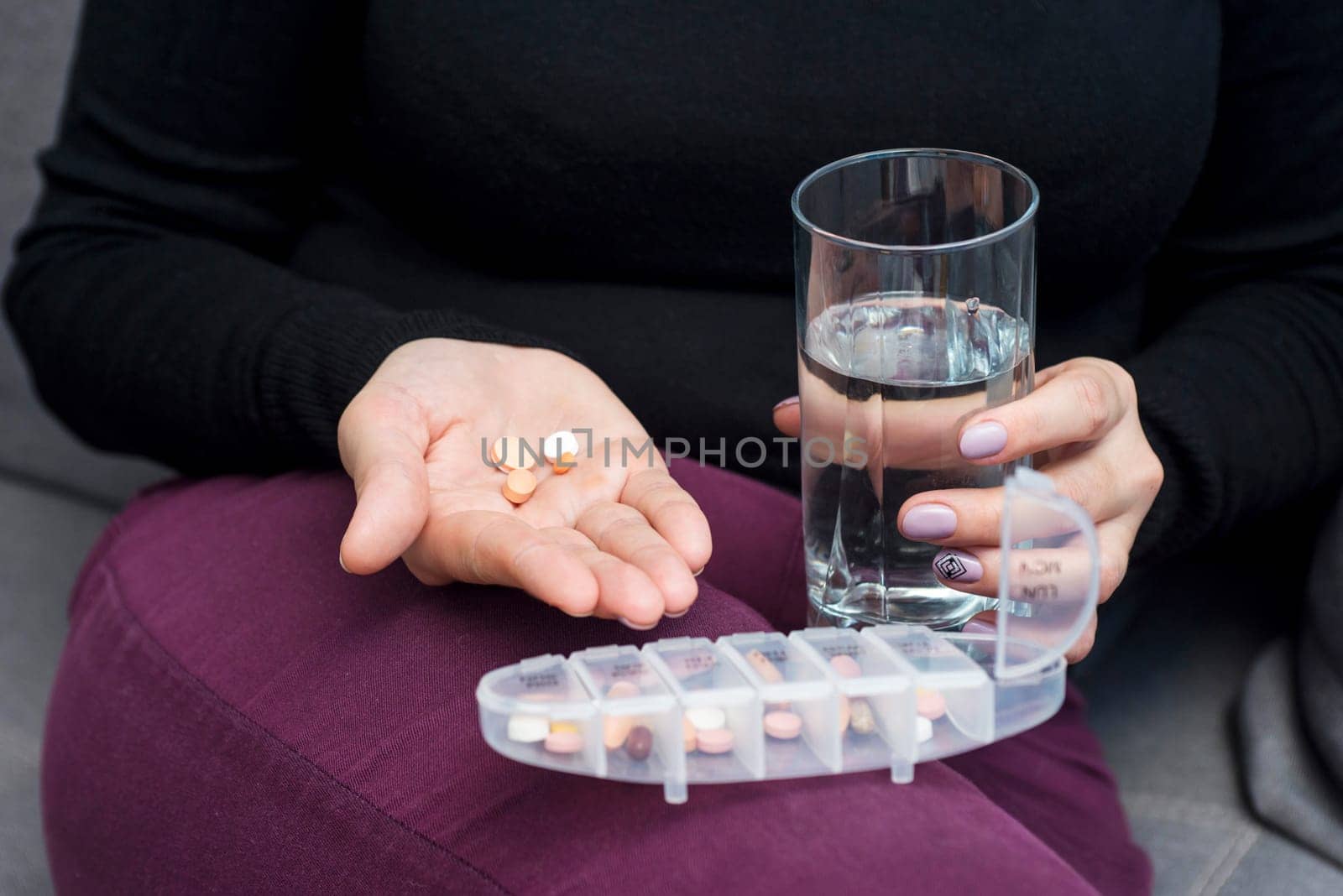 Woman holds tablet and glass of water. Female going to take tablet from headache or painkiller or abortion pill medication drinking clear water from glass.