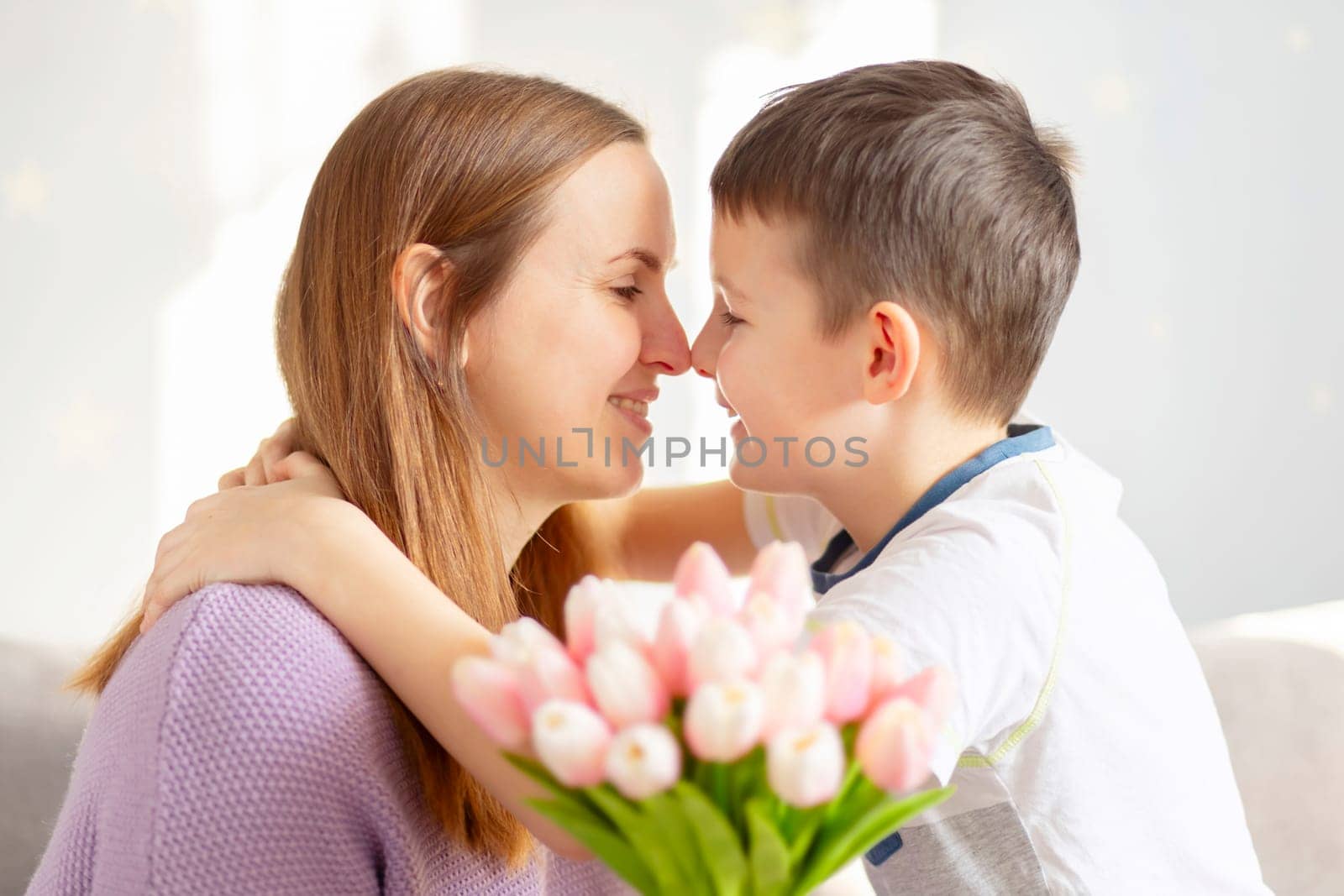 Cute son giving his mother bouquet of tulips congratulating her on mothers day by andreyz