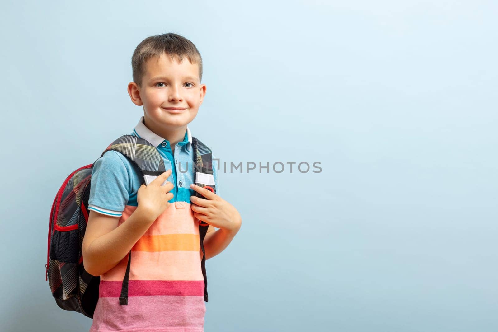 Happy smiling schoolboy with backpack on blue background. School concept by andreyz