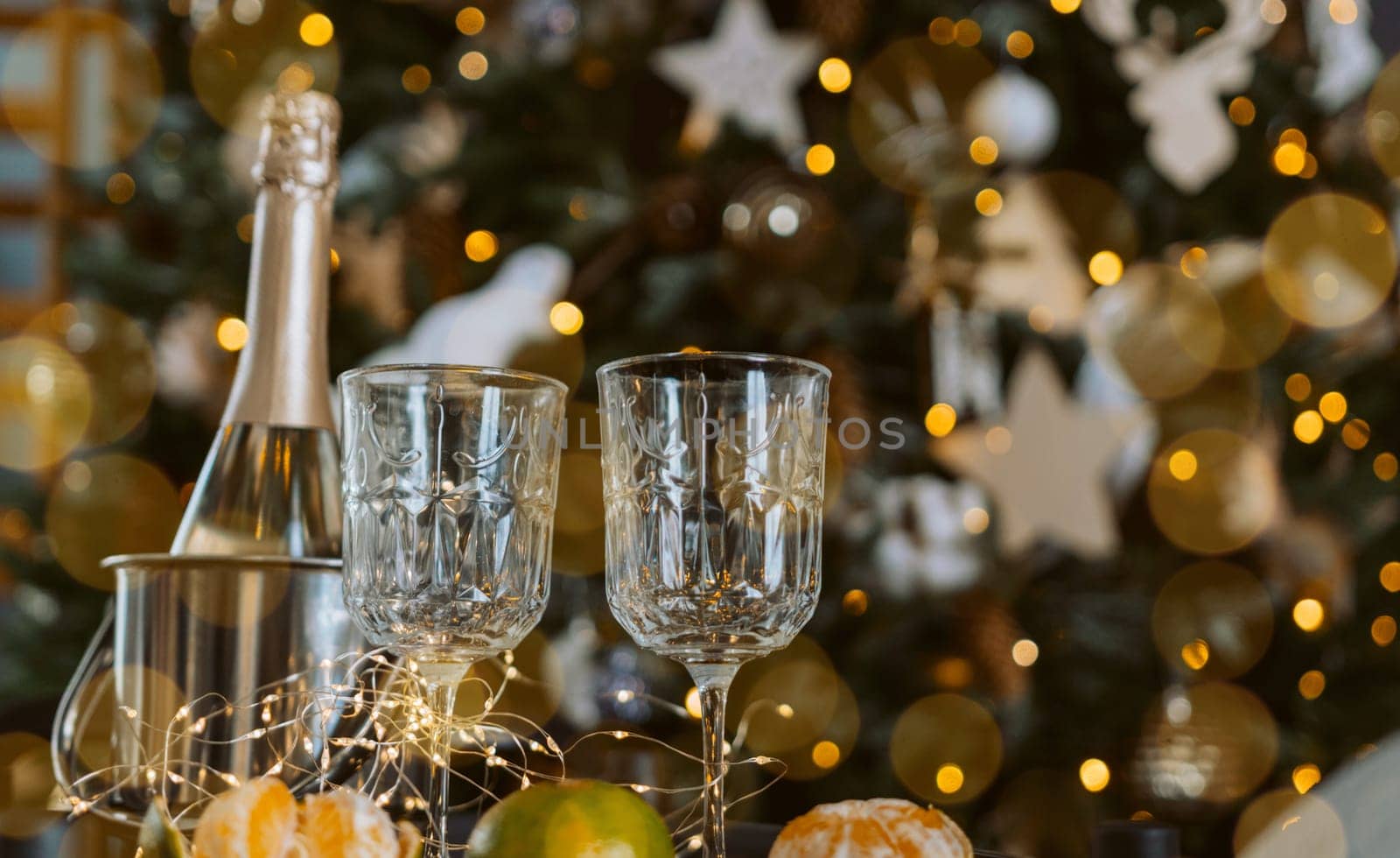 Champagne glasses, New Year decor. New Year's festive setting, family holidays.Two glasses of champagne are on the table against the background of New Year's decorated tree