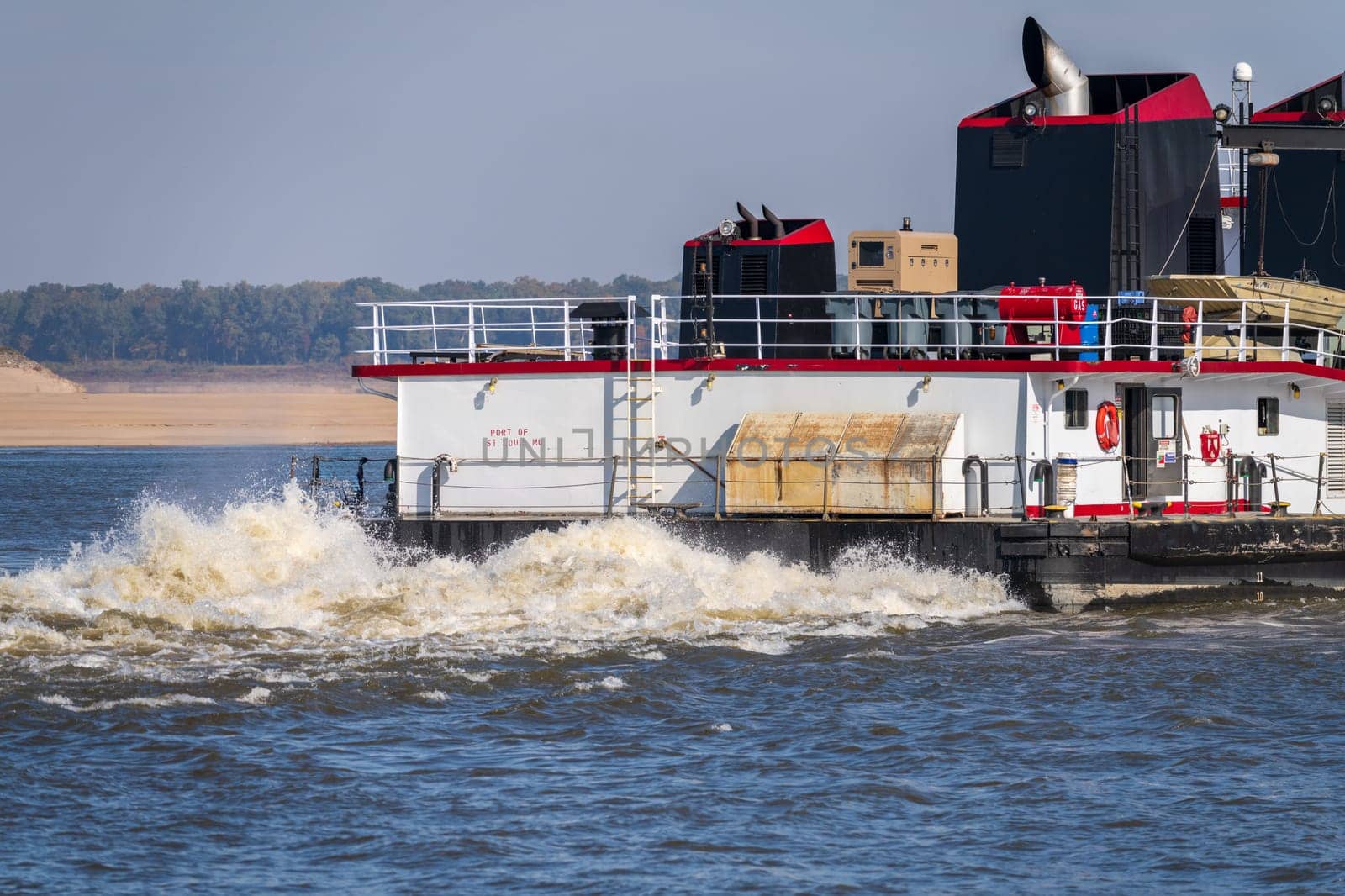 Detail of the stern of a pusher boat or tugboat churning the Mississippi river in Missouri with sand bar