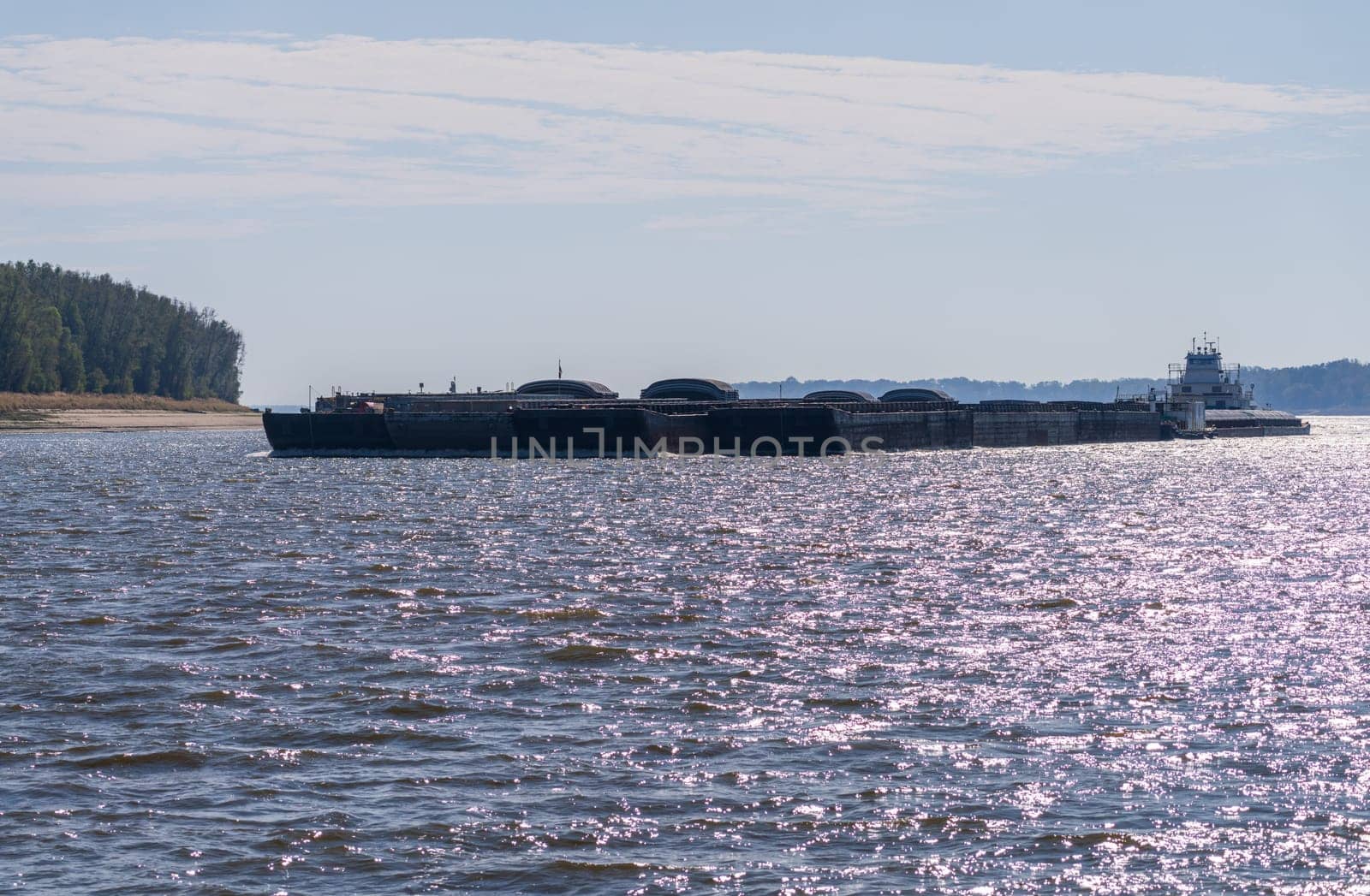 Panorama of sand banks due to extreme low water conditions on Mississippi river in October 2023 with a large barge rounding a bend near Greenville, MS