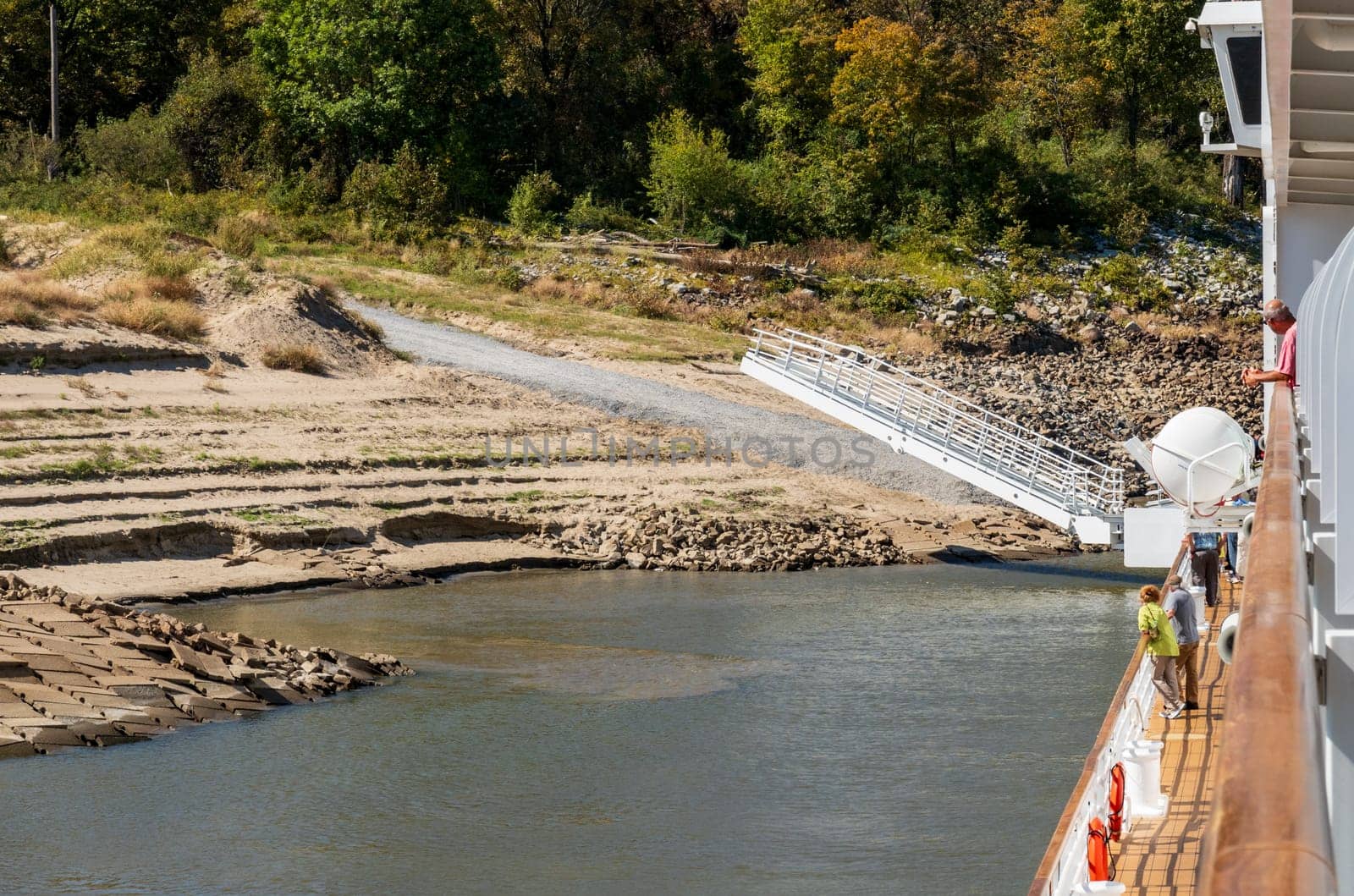 Modern Mississippi river boat starts to dock with gangway on river bank with steep sandy side in Arkansas