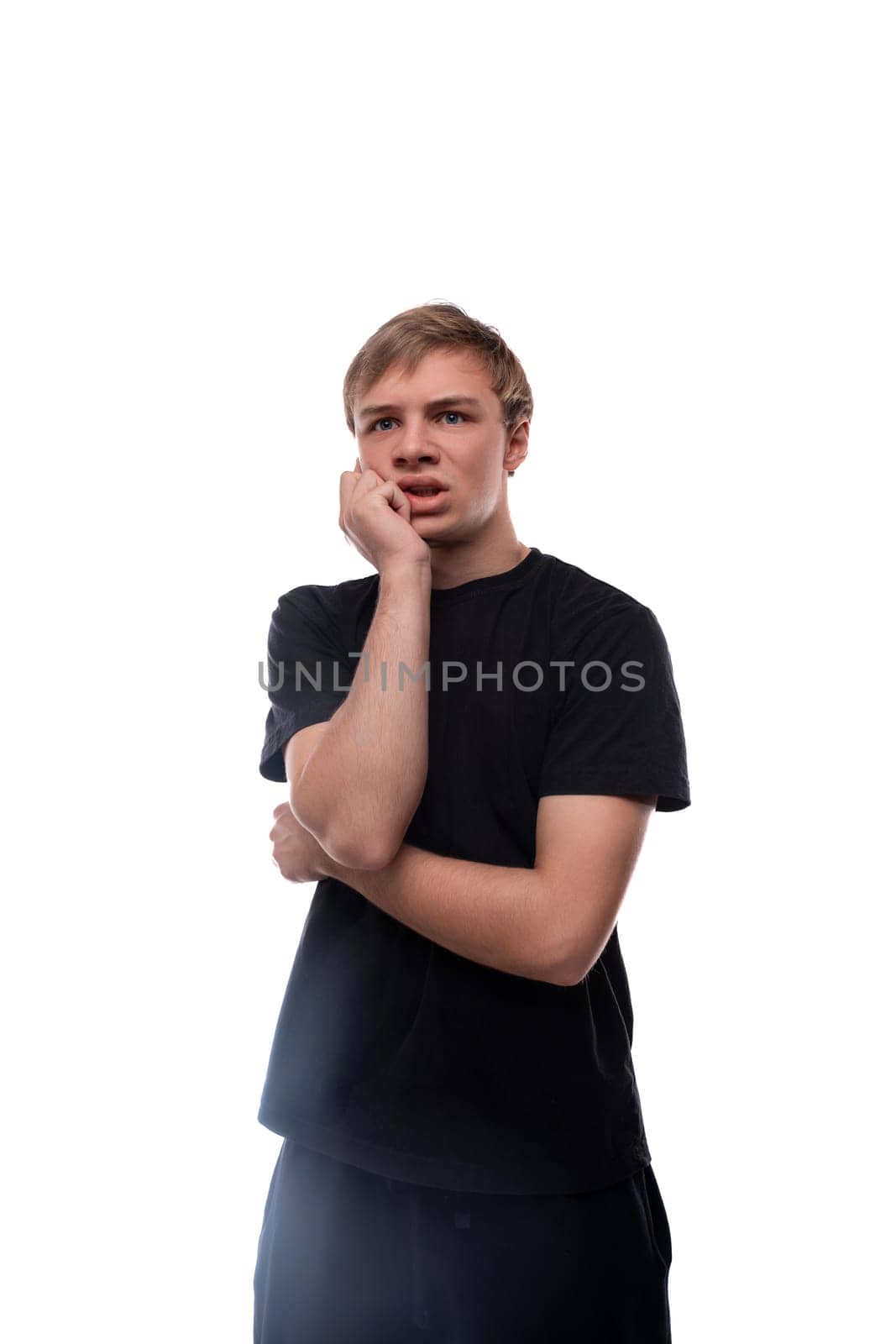 European blond teenager boy dressed in a black T-shirt on a background with copy space.