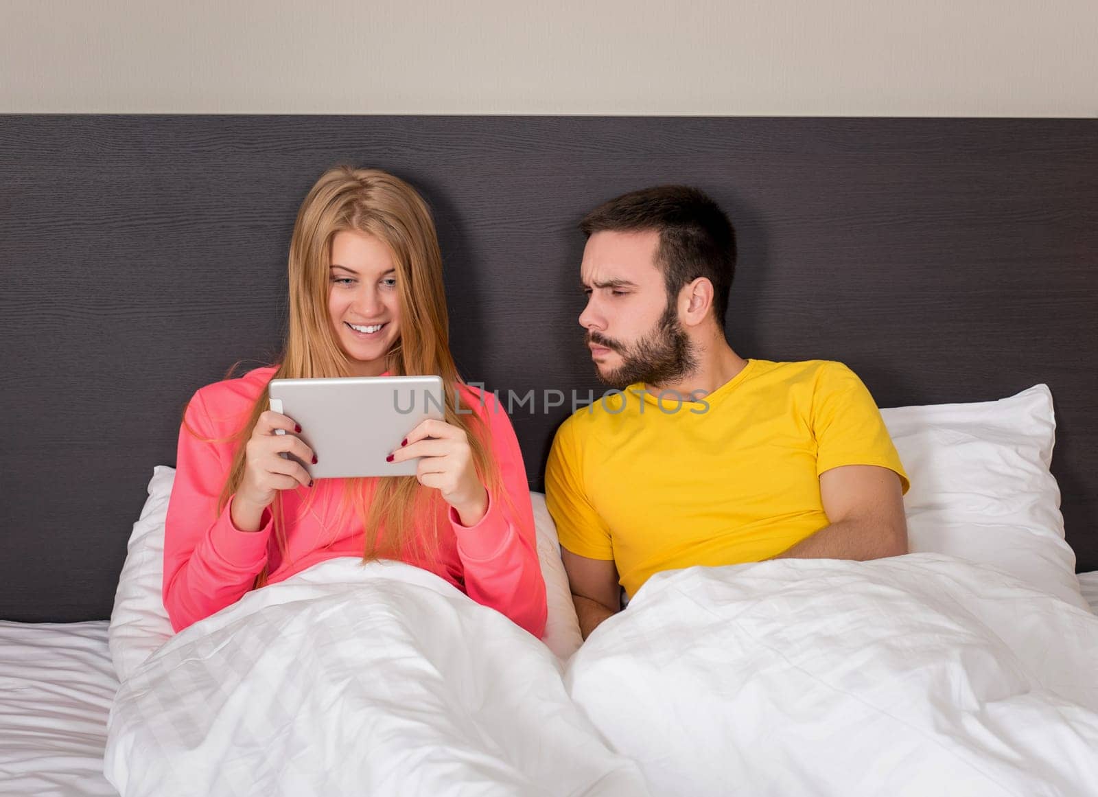 Young Sweet Couple at Bed Watching Something on Tablet Gadget by nazarovsergey