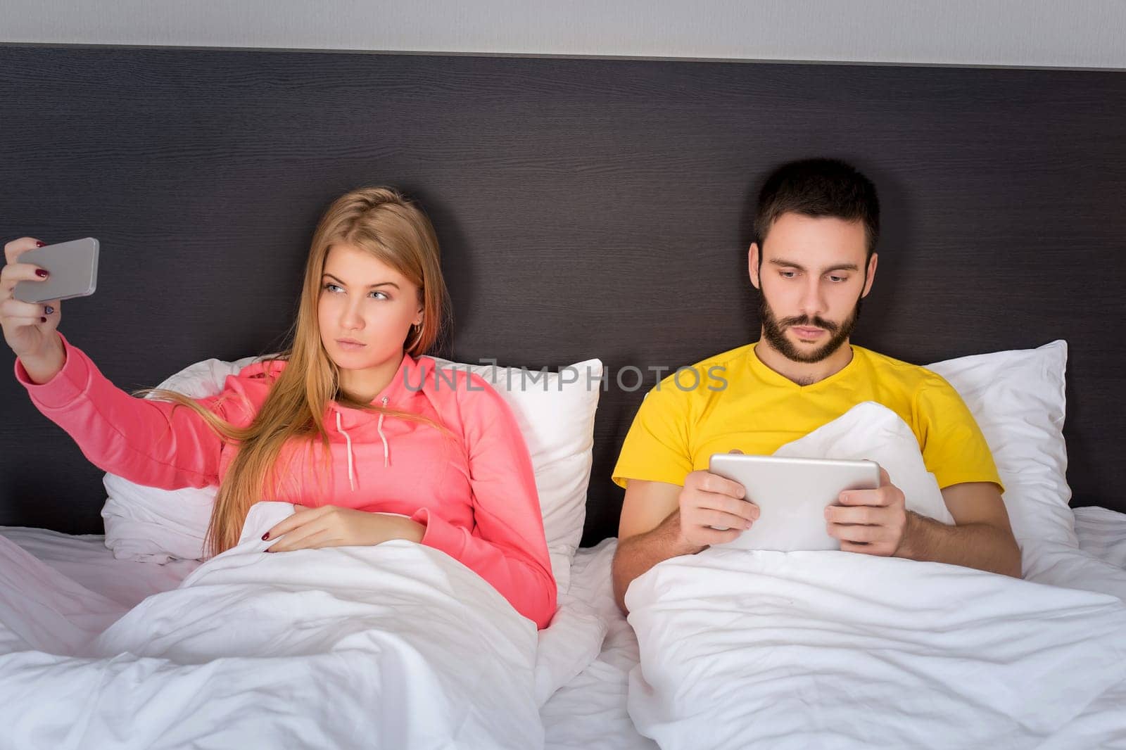 Young happy couple on bed doing selfie with telephone camera. Concept about technology and people