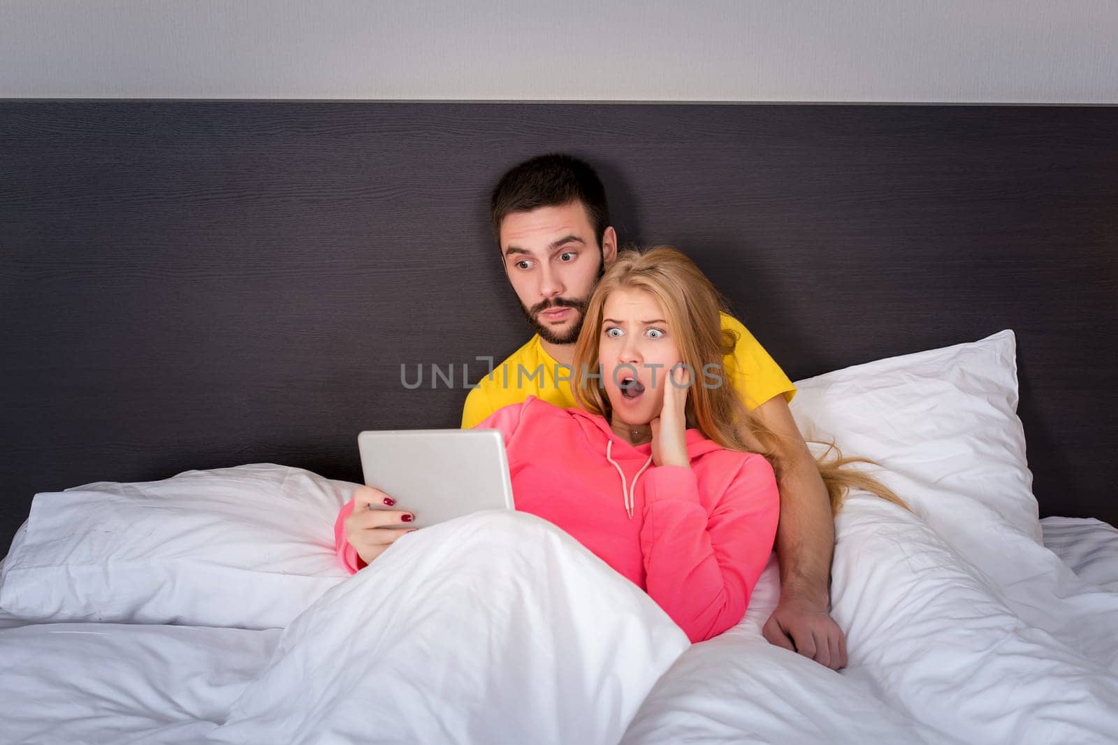 Young Sweet Couple at Bed Watching Something on Tablet Gadget by nazarovsergey
