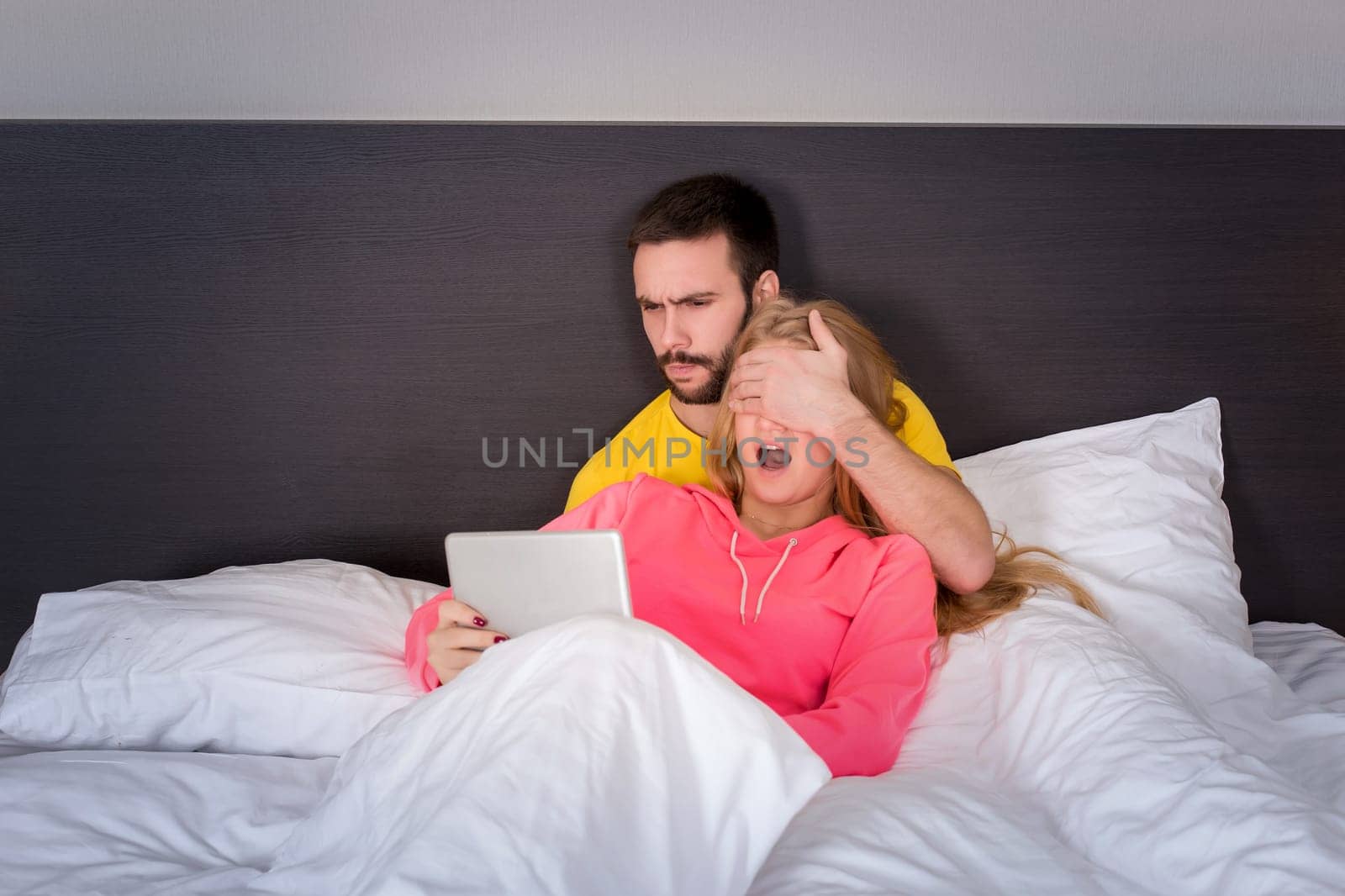 Young Sweet Couple on Bed Watching Something on Tablet Gadget. Concept about technology and people