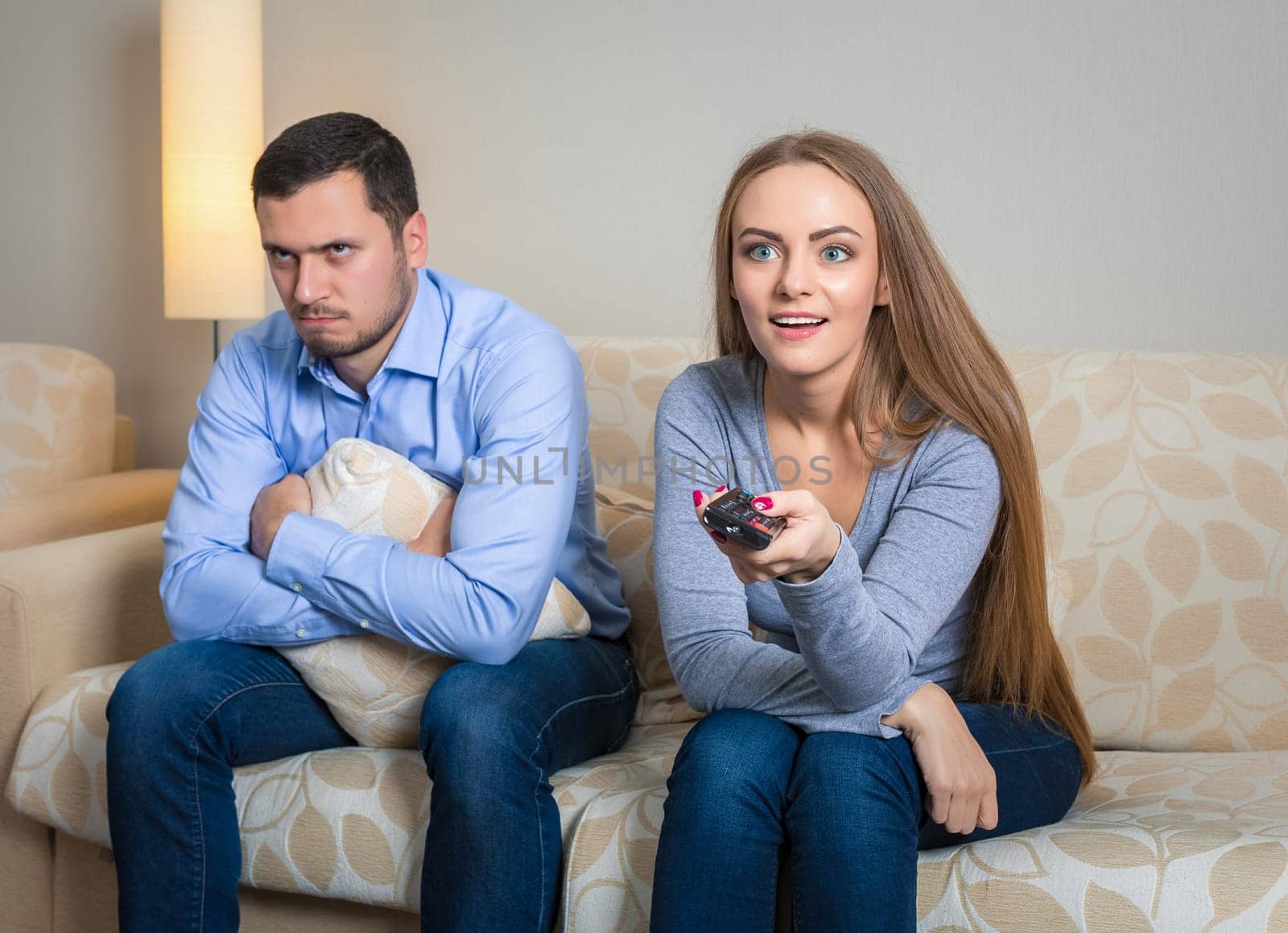 Portrait of couple sitting on sofa watching television. by nazarovsergey