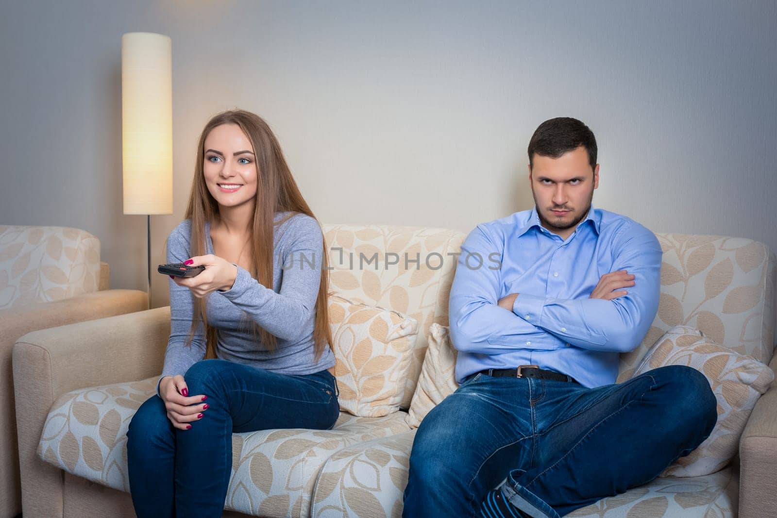 Portrait of couple sitting on sofa watching television. by nazarovsergey