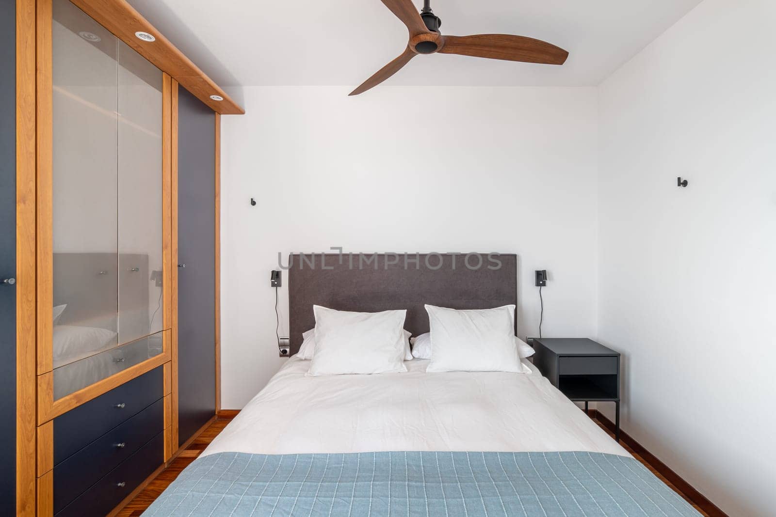 Soft double bed, closet and ceiling fan in cosy hotel room by apavlin