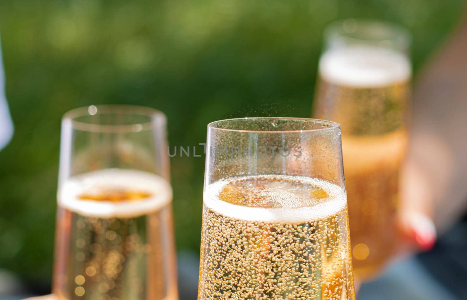 Close up view of a single flute glass of champagne outdoors isolated against a garden scene blurred in the background. High quality photo. High quality photo