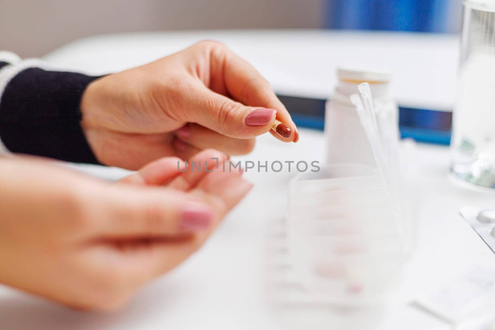 The woman places pills in an open pill organizer or plastic pill box. Sorting pills for daily use according to the doctor's prescription