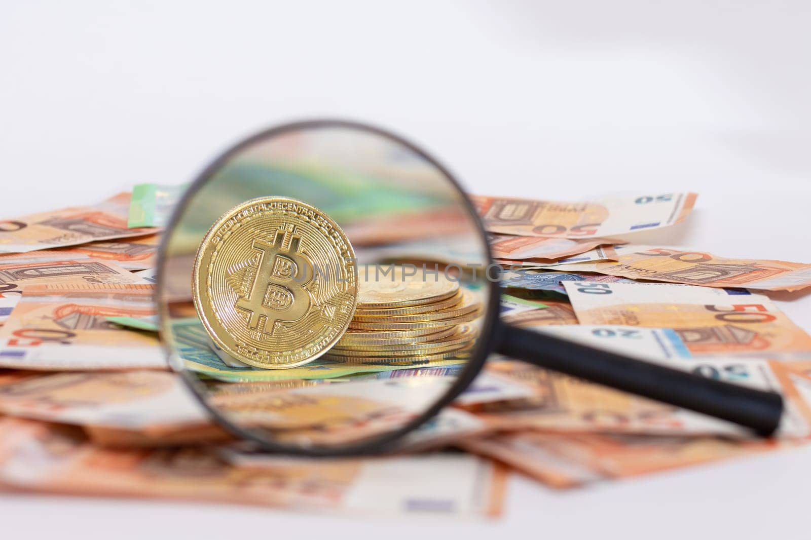 A Stack of Bitcoin Coins Visible Through a Magnifying Glass on the 50-Euro Banknotes. Euro Currency and Crypto Currency. Orange Paper Money. A Lot of Fifty-Euro Bills. Anonymous Payments Concept