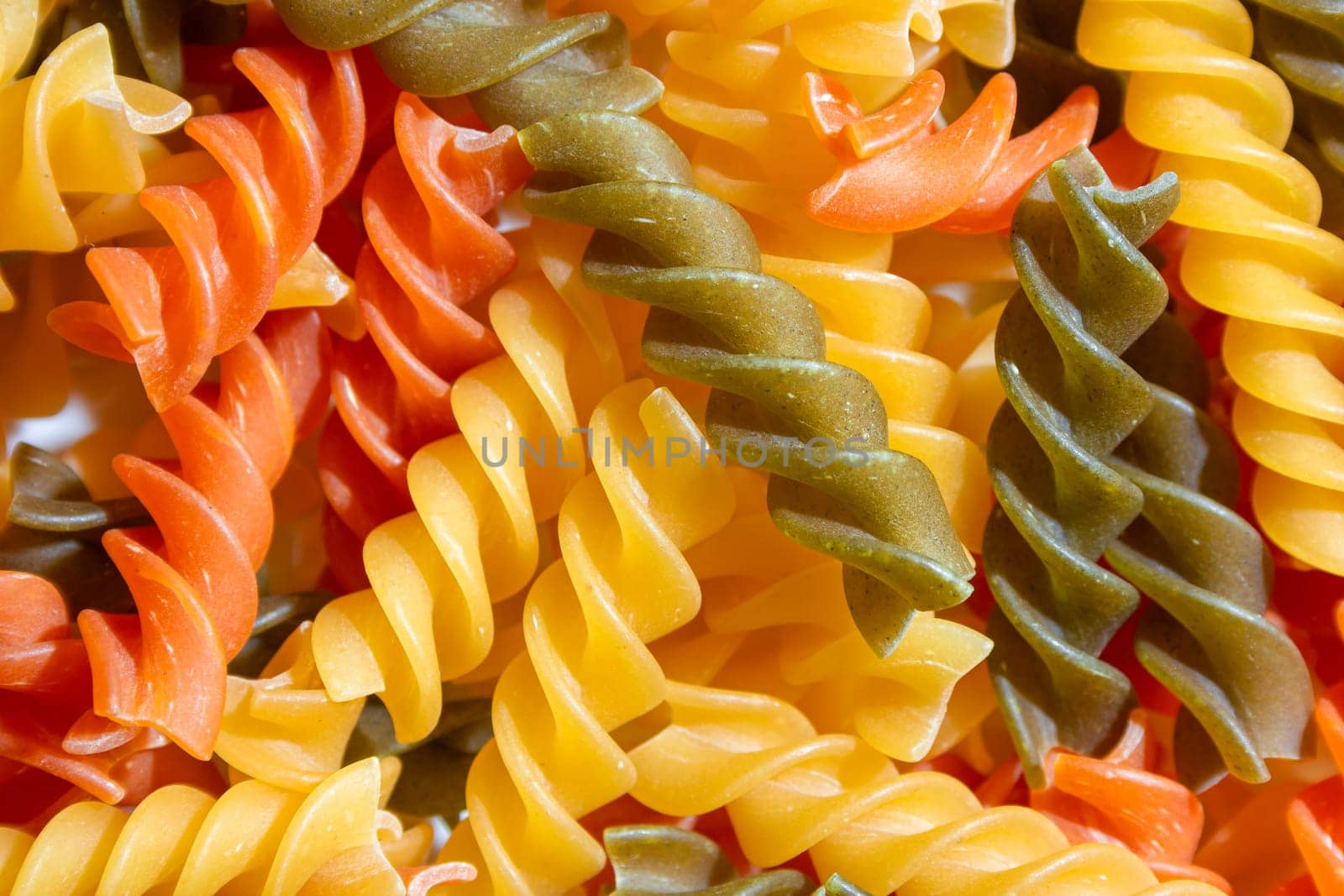 Uncooked Vibrant Colored Fusilli Pasta Background by InfinitumProdux