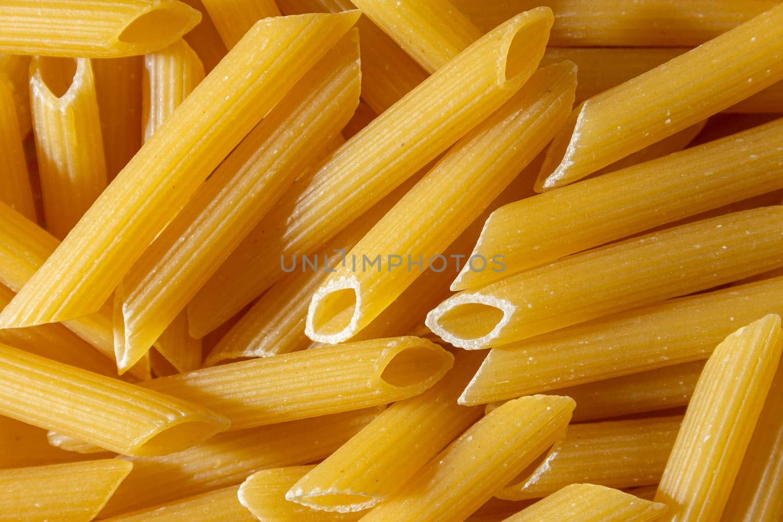 Uncooked Penne Rigate Pasta: A Culinary Canvas of Penne Macaroni, Creating a Lively and Textured Background for Gourmet Cooking. Dry Pasta. Raw Macaroni - Top View, Flat Lay