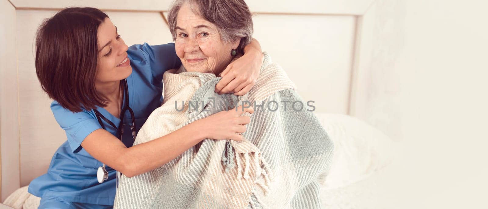 A smiley young nurse takes care of an elderly 80-year-old woman at home, talks about the threatment. Happy retired woman and trust between doctor and patient. Medicine and healthcare.