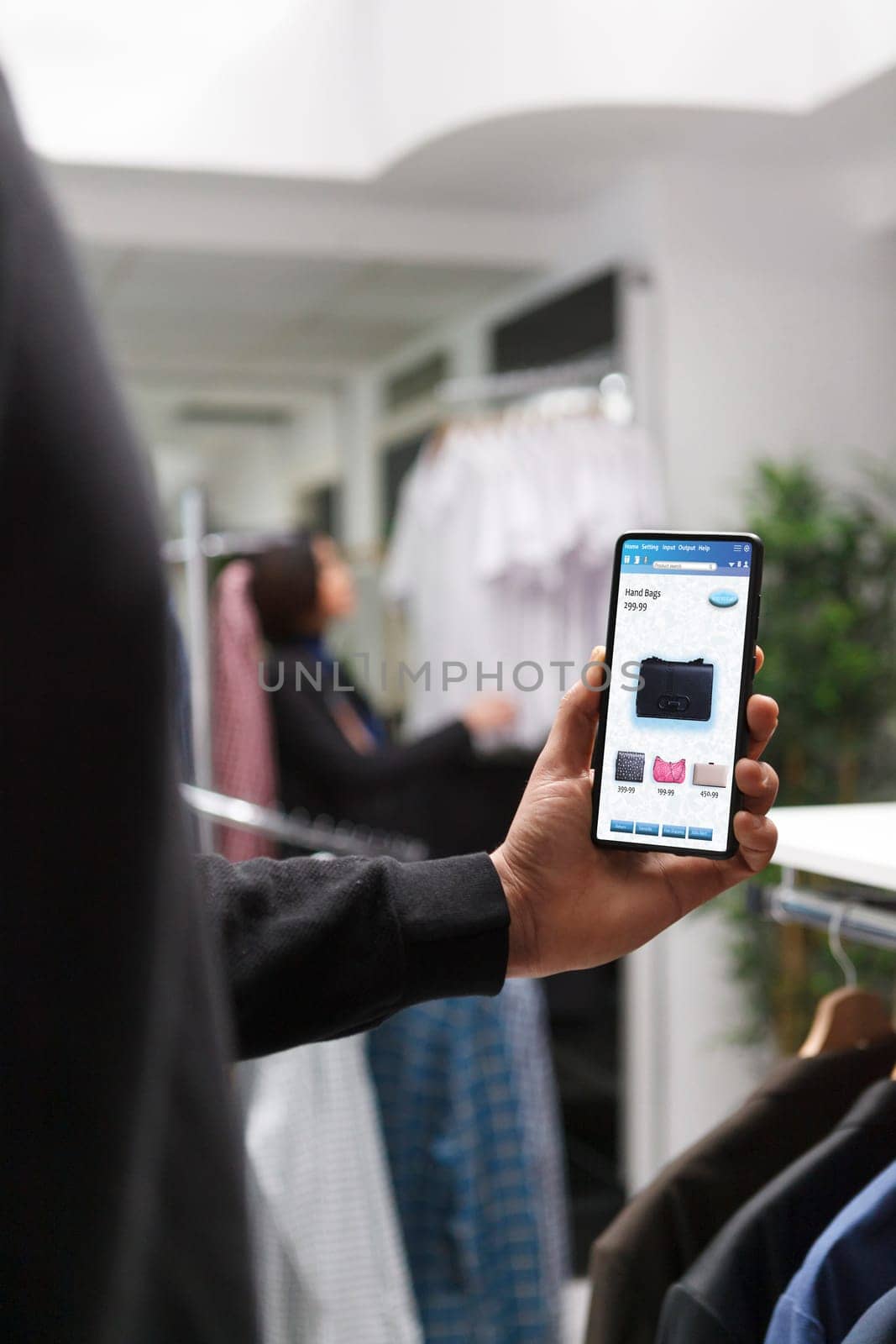 Selective focus of caucasian customer holding digital device in modern boutique. Stylish male shopper browsing for fashionable merchandise in clothing store with assistance from modern technology.