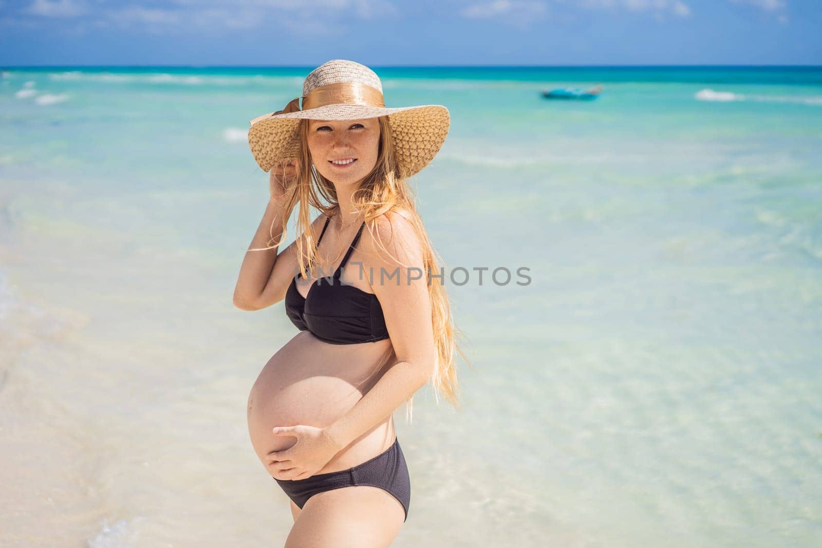 Radiant and expecting, a pregnant woman stands on a pristine snow-white tropical beach, celebrating the miracle of life against a backdrop of natural beauty.