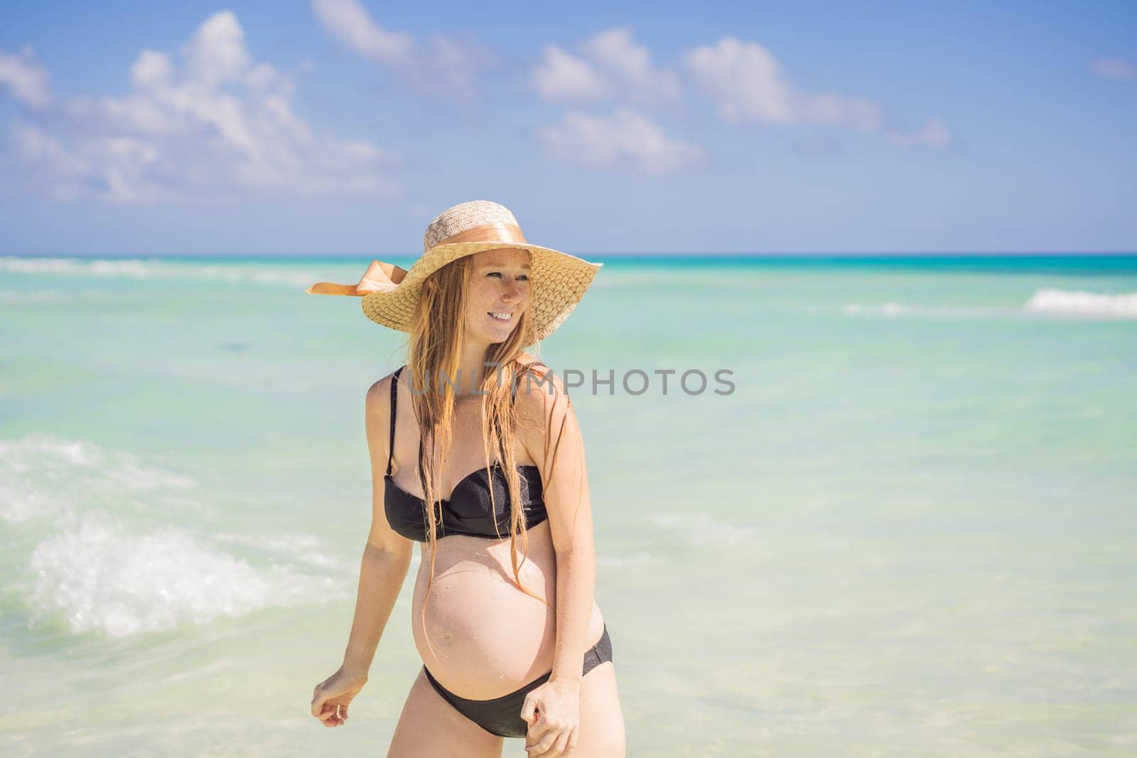 Radiant and expecting, a pregnant woman stands on a pristine snow-white tropical beach, celebrating the miracle of life against a backdrop of natural beauty by galitskaya