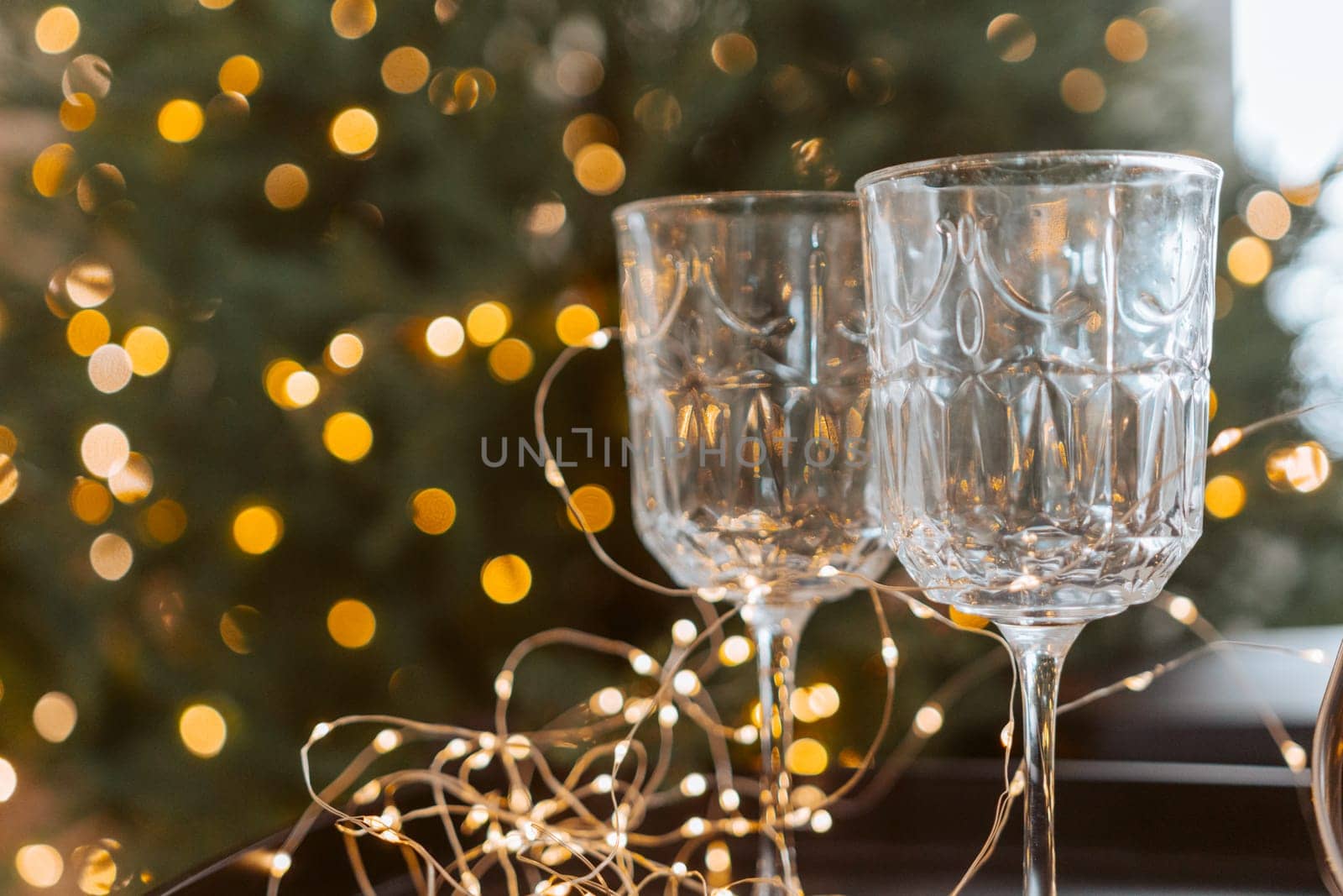 Champagne glasses, New Year decor. New Year's festive setting, family holidays.Two glasses of champagne are on the table against the background of New Year's decorated tree