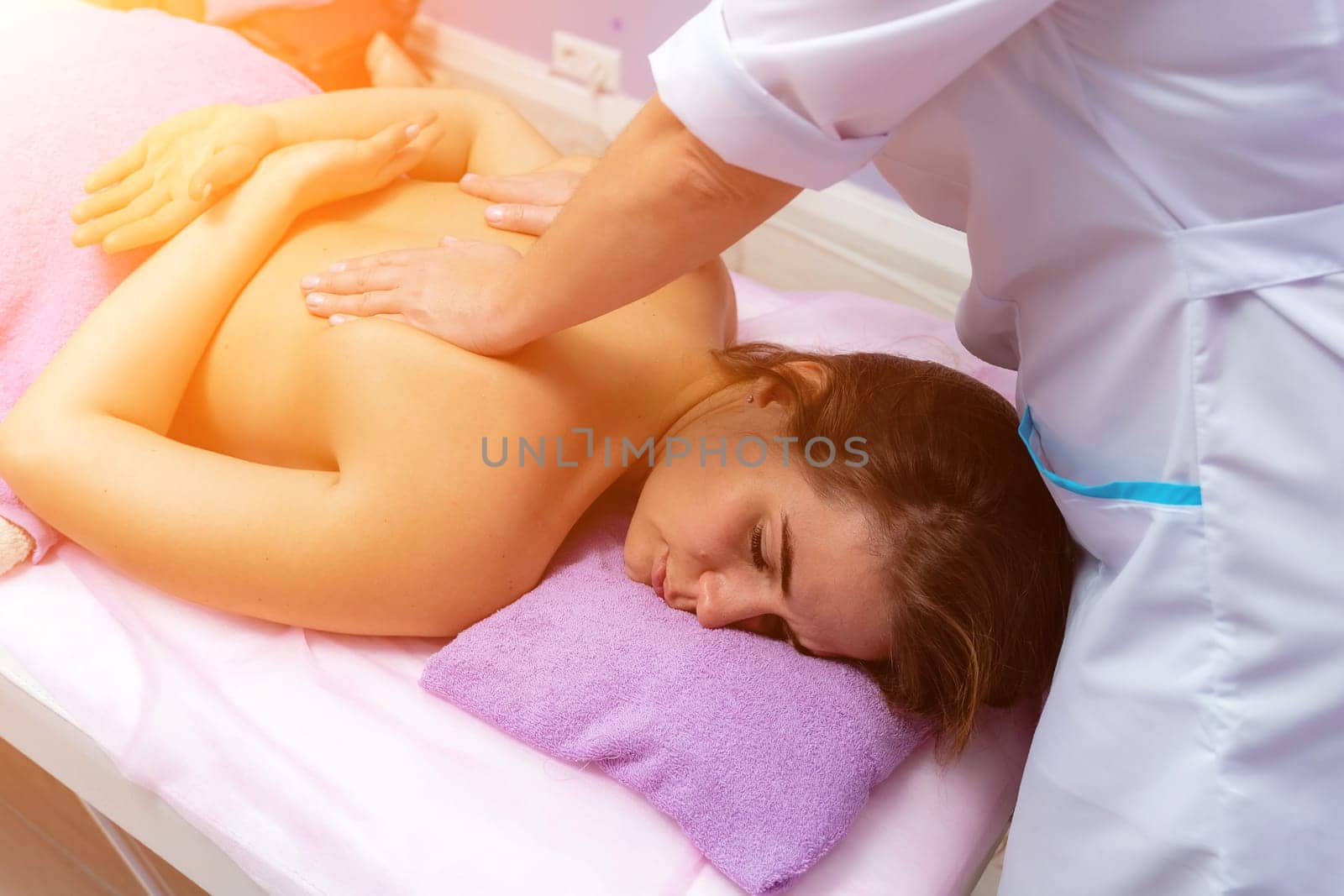 Blonde massage therapist massaging a woman. Woman getting a massage at the spa.